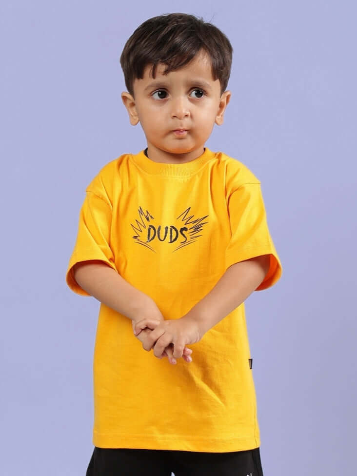 Boy wearing mustard 'Mufasa' T-shirt for boys & girls by DUDS, showcasing playful design and bright color.