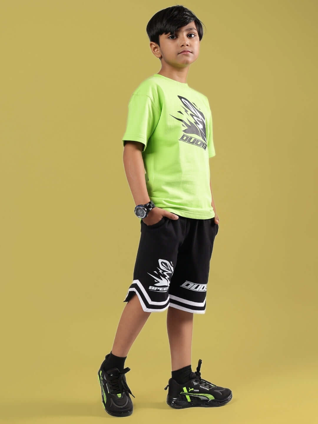Child wearing neon green and black muffin co-ord set designed by DUDS, featuring a t-shirt and shorts, perfect for boys and girls.