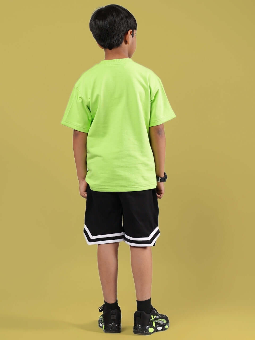 Child wearing MUFFIN CO-ORD FOR BOYS & GIRLS NEON GREEN-BLACK outfit, showcasing vibrant neon green shirt and black shorts.