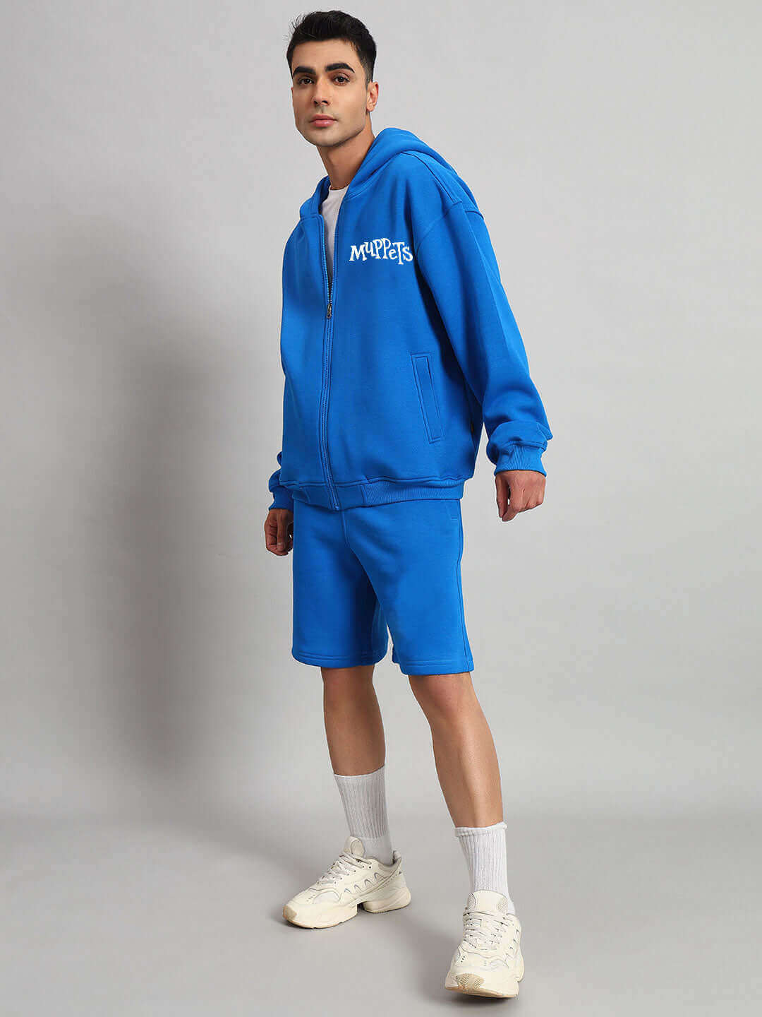 Man wearing blue Muppet fleece co-ord set featuring hoodie and shorts, customized fit by DUDS, stylish casual outfit.