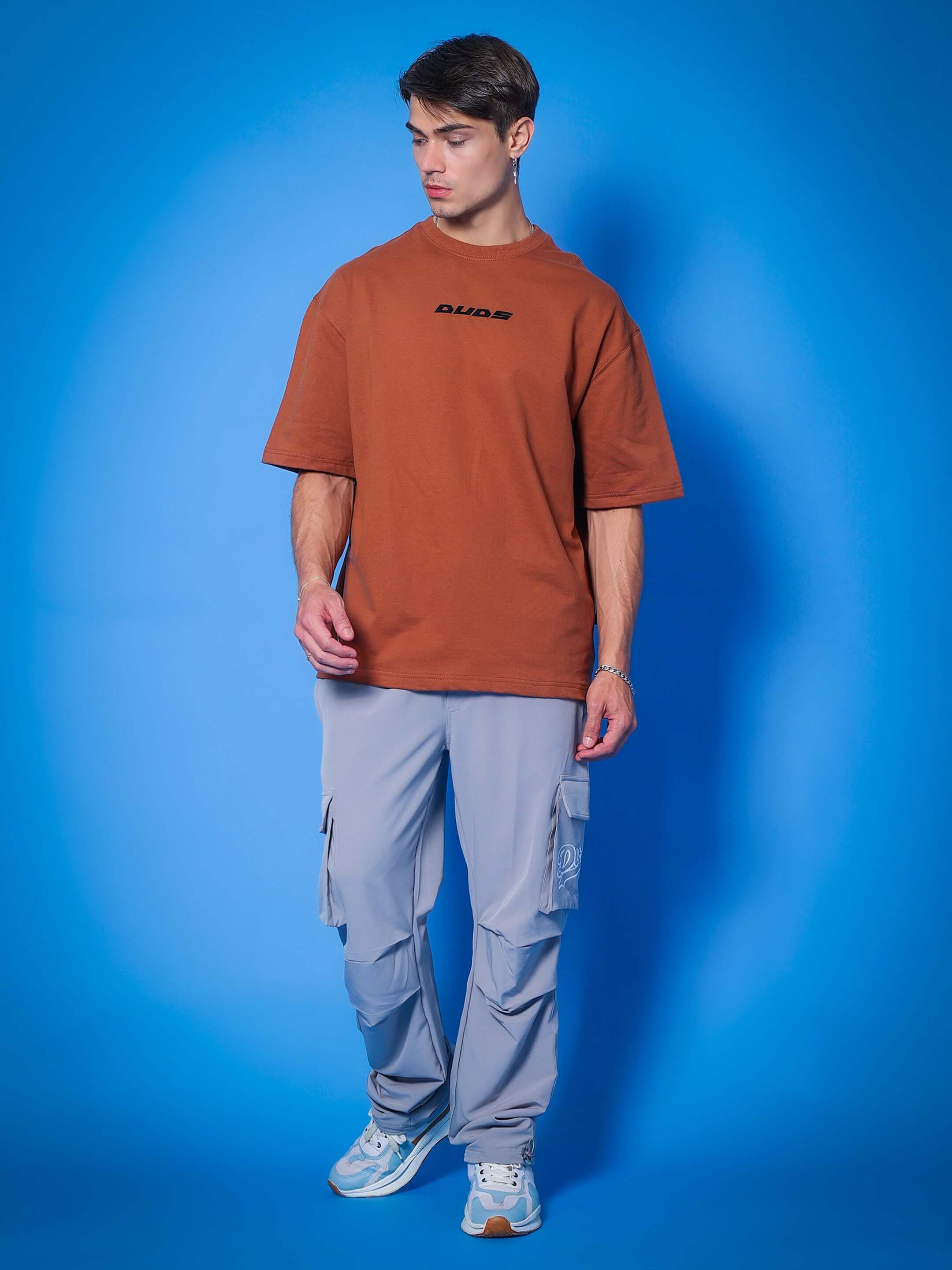 Man wearing Myriad relaxed fit grey cargo pants and brown T-shirt.