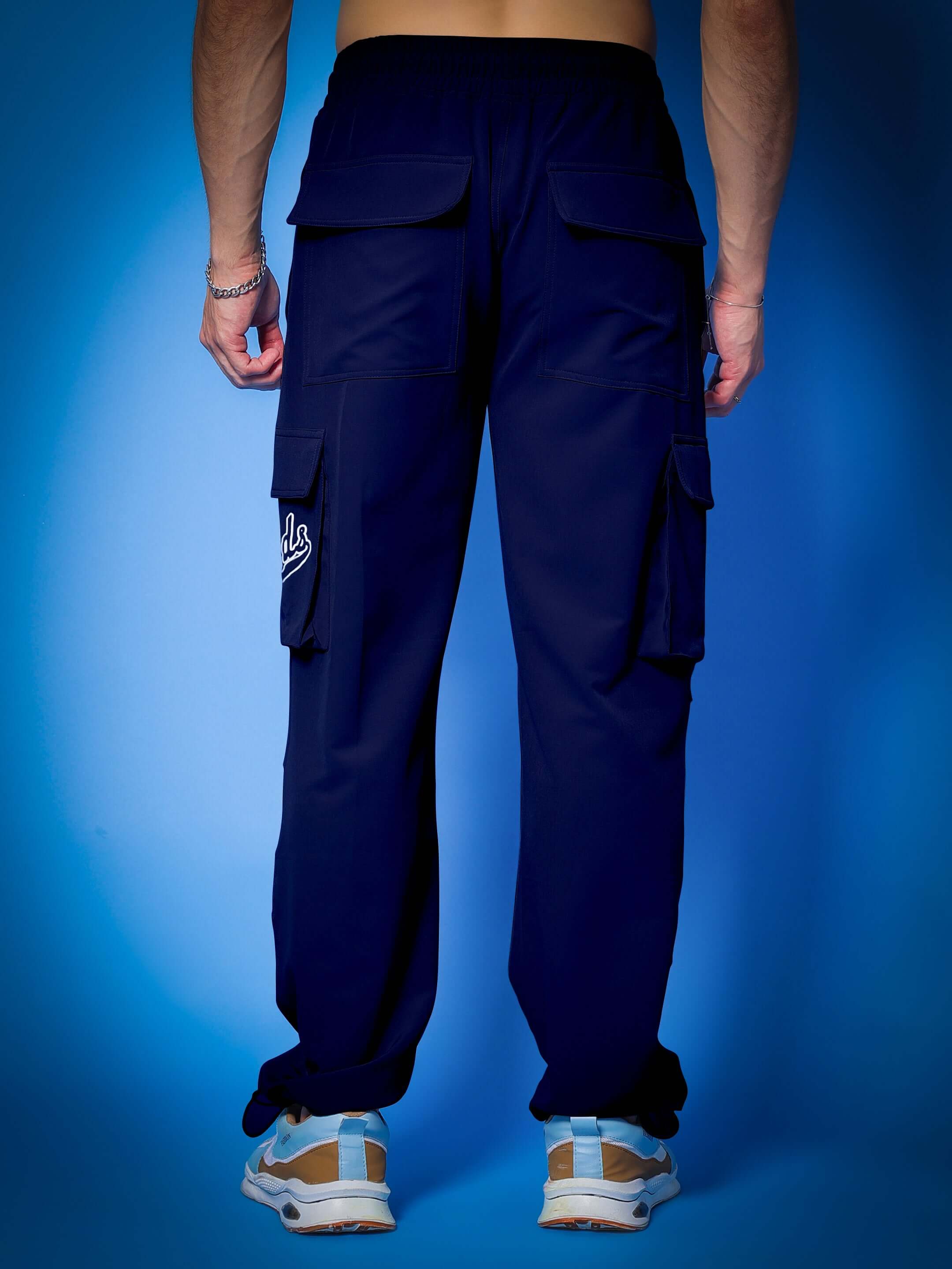 Back view of person wearing MYRIAD RELAXED FIT CARGO PANTS NAVY BLUE, showcasing relaxed fit and multiple pockets.