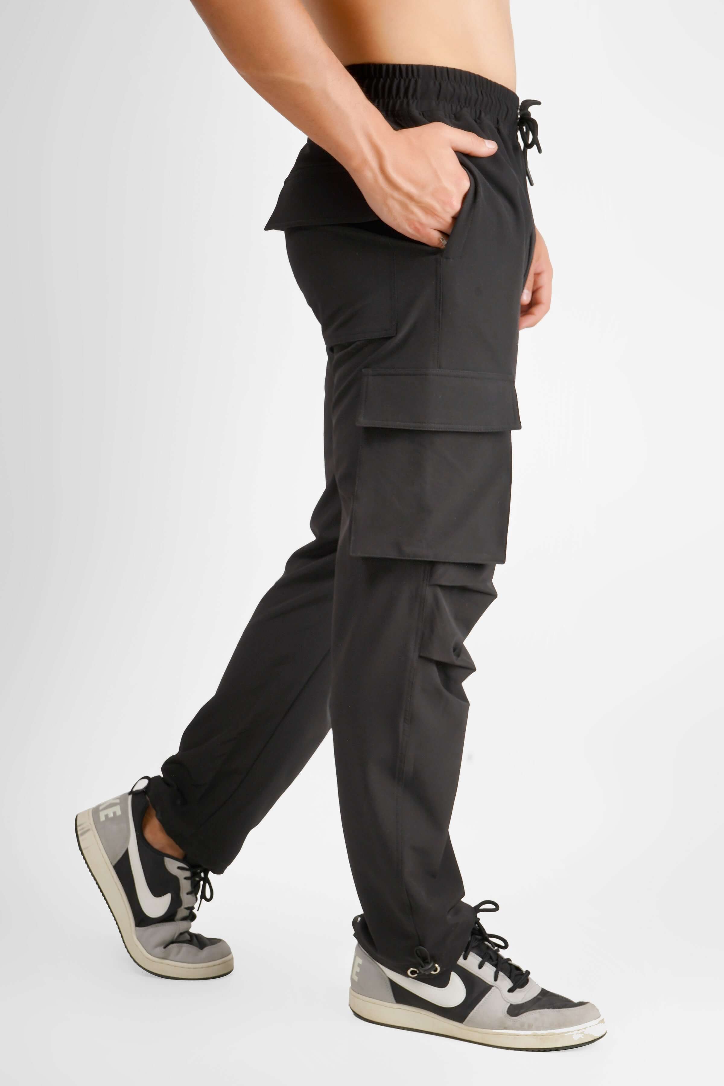 Side view of a person wearing MYRIAD Relaxed Fit Cargo Pants in dark grey, showcasing pocket details and drawstring waist.