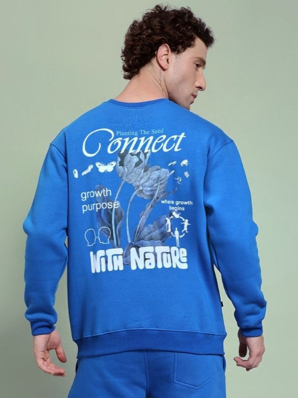 Man wearing NATURE LINK FLEECE SWEATSHIRT ROYAL BLUE with nature-inspired back design, ideal for comfort and style.
