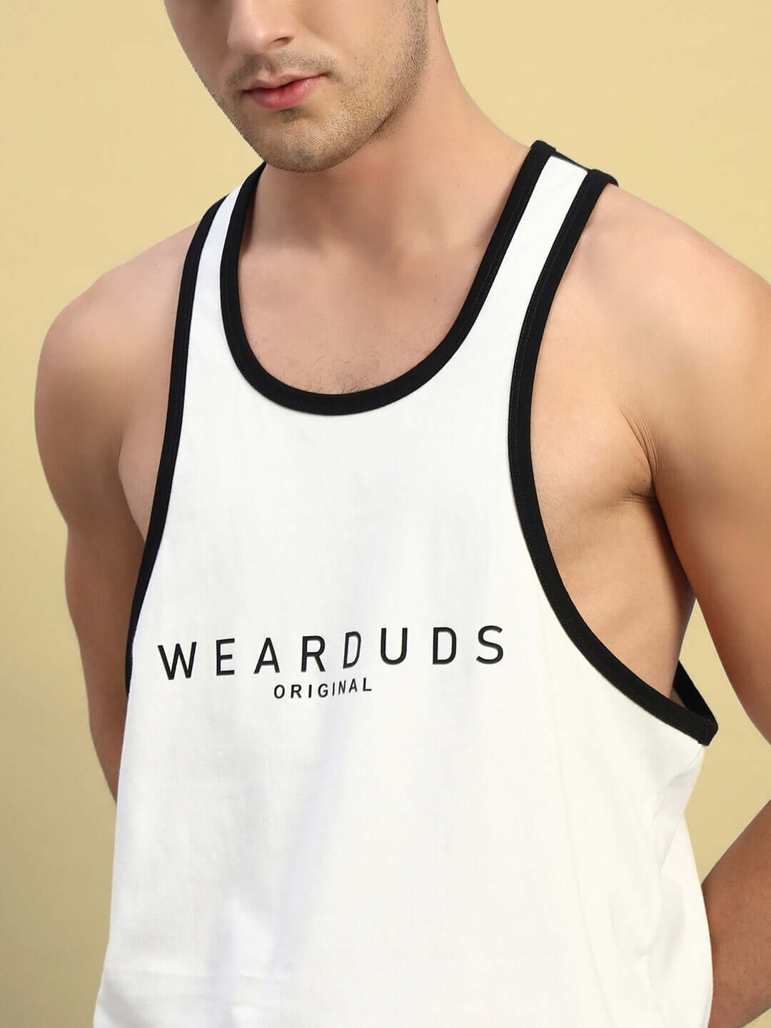 Man wearing NEO GYM T-SHIRT in off-white with black trim and WEARDUDS logo, showcasing athletic design and custom fit option.