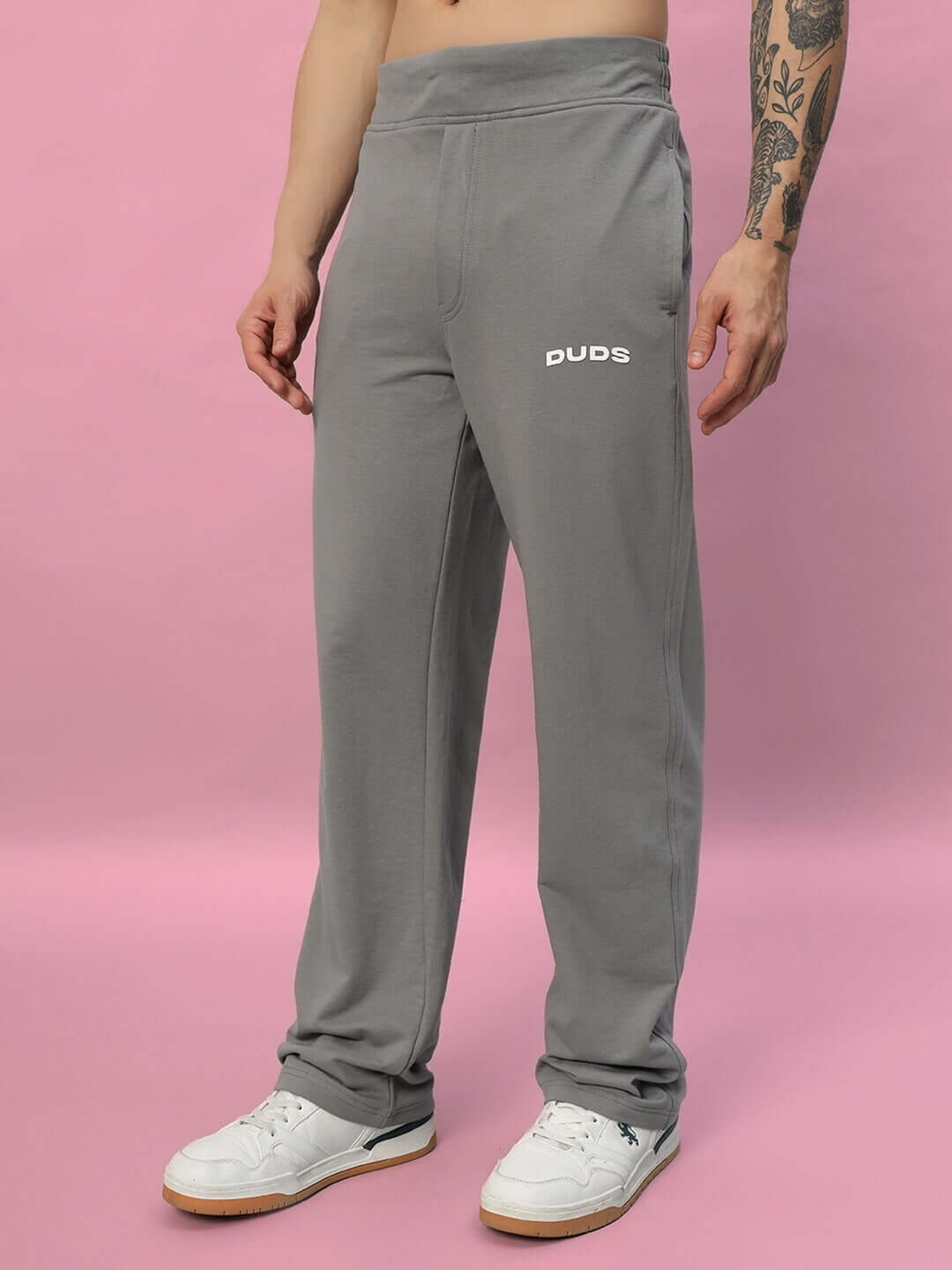 Model wearing New Era Relaxed Fit Grey Joggers by DUDS, ideal for comfort and customizable fit, against a pink background.