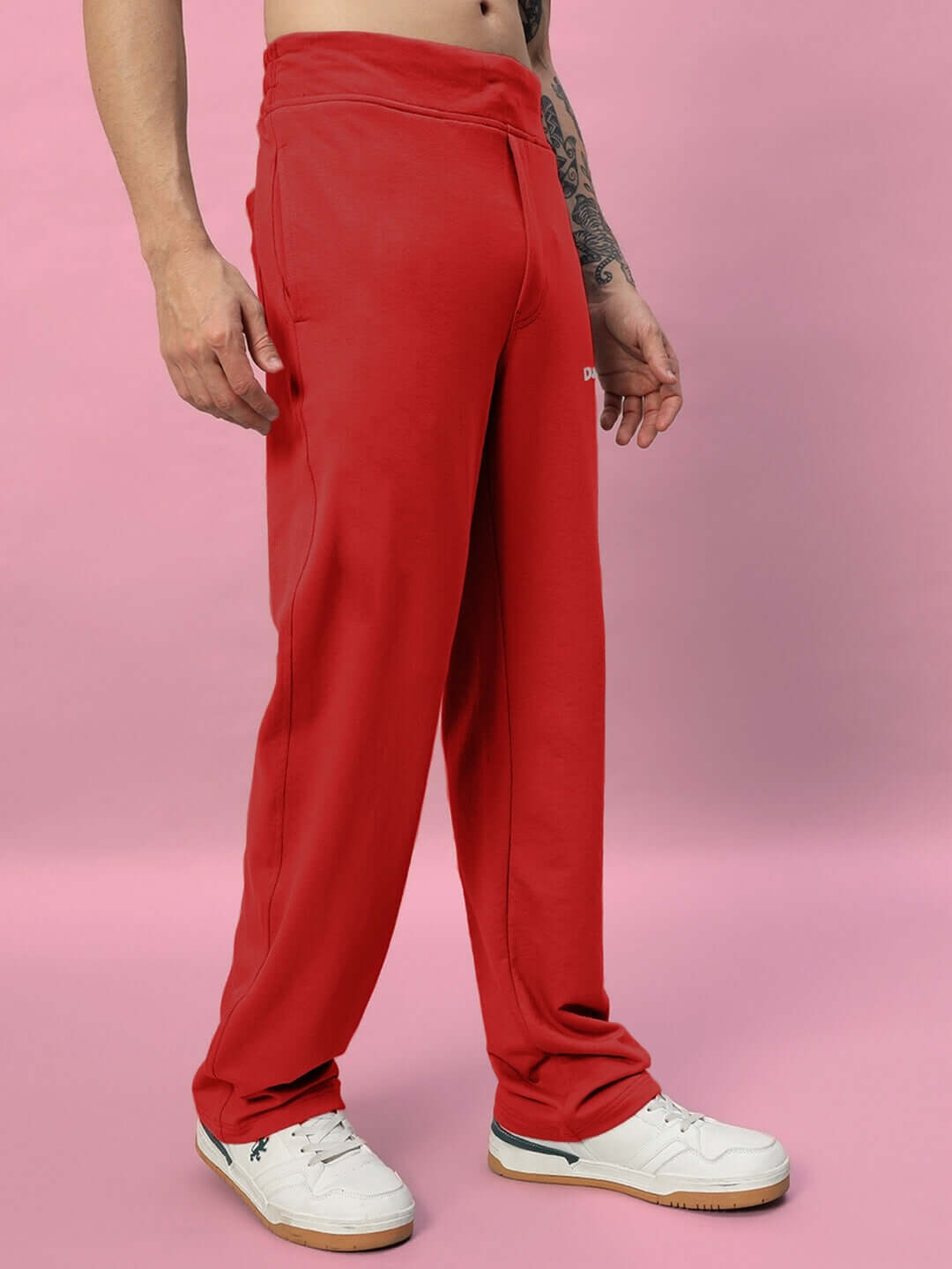 Model wearing red New Era Relaxed Fit Joggers, made-to-order with custom size options by DUDS, standing against a pink backdrop.