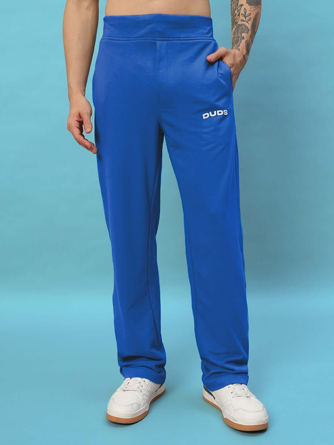 Man wearing NEW ERA RELAXED FIT JOGGERS ROYAL BLUE for comfort and style on blue background.