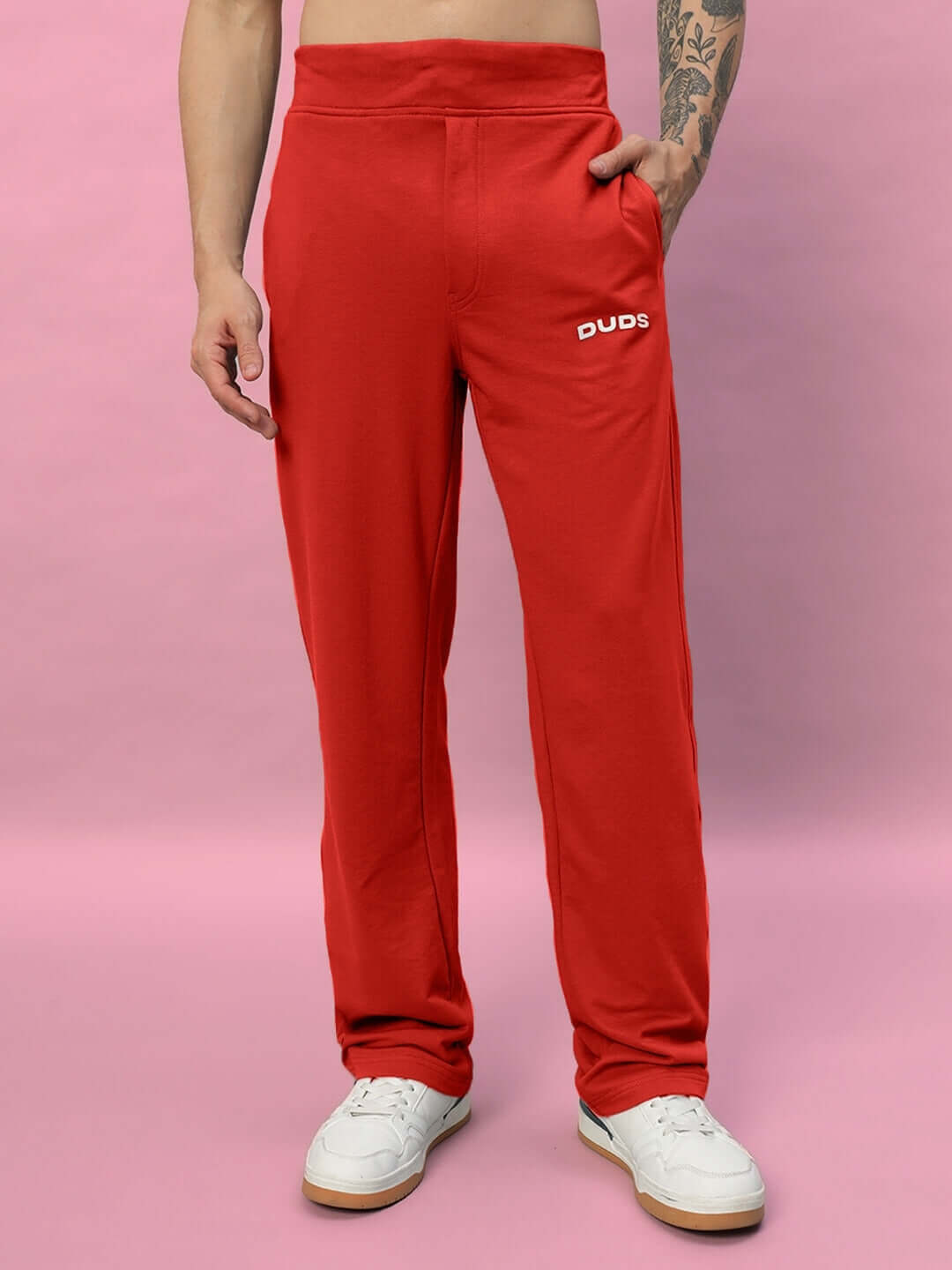 Red relaxed fit joggers by DUDS, made-to-order with custom fit option, displayed against pink background.