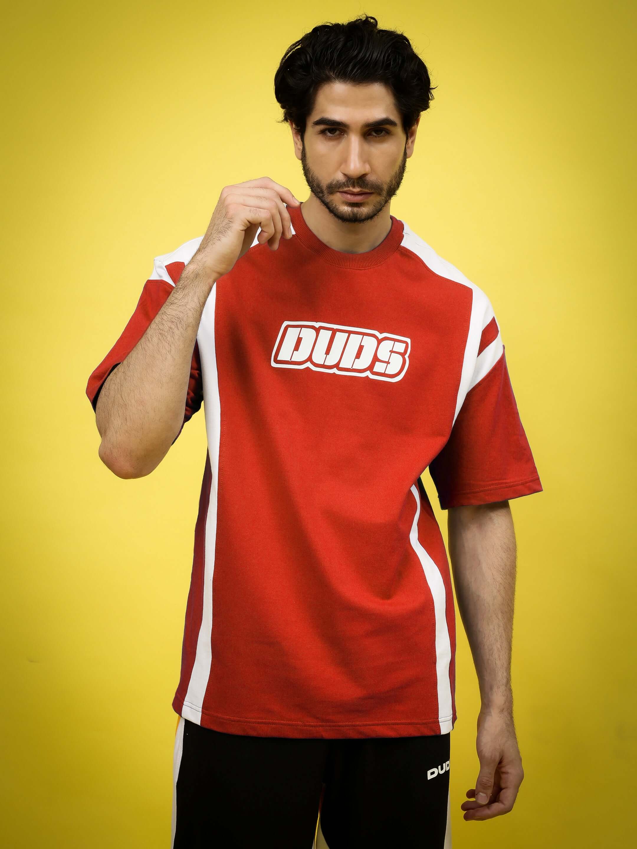 Red oversized t-shirt with 'Duds' logo, made from premium heavy gauge fabric, modeled against a yellow background.