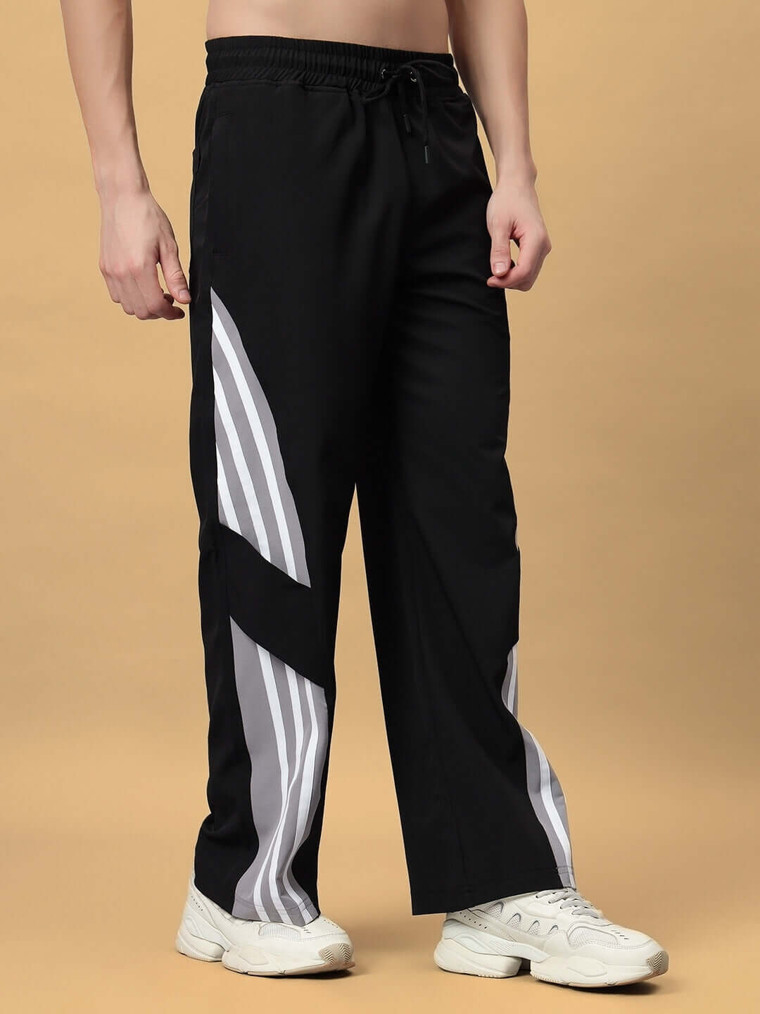 Person wearing black relaxed fit cargo pants with gray stripes, showcasing customizable size options.