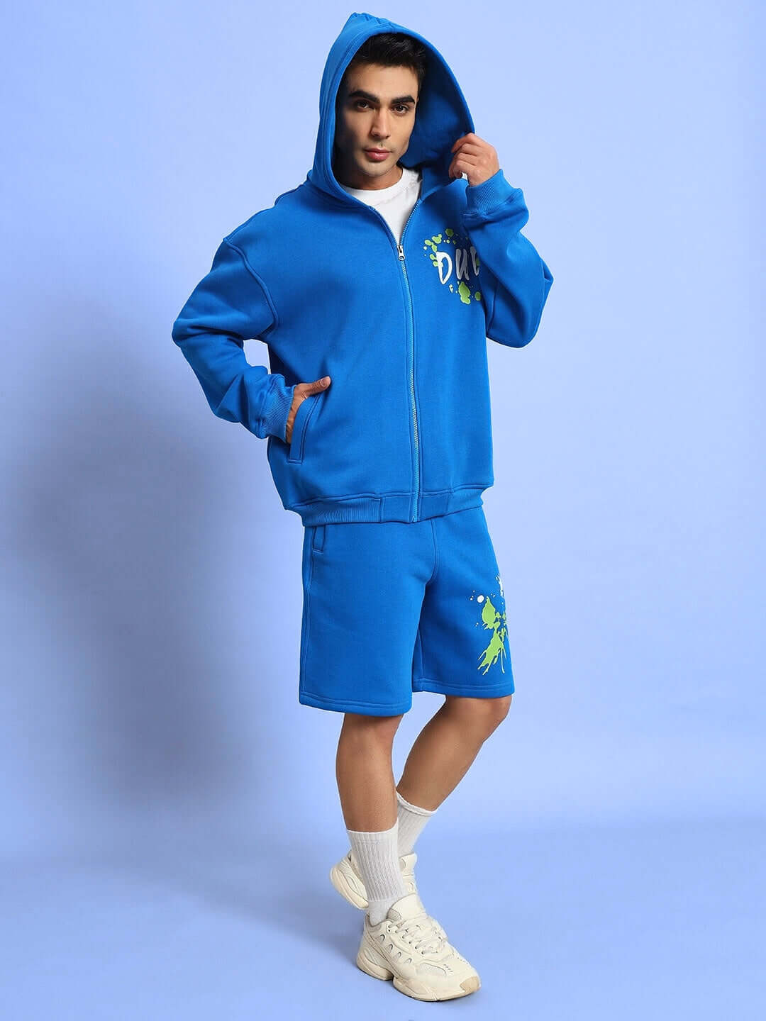 Person wearing a R-Blue No Drama Cotton Fleece Hoodie with matching shorts, posing against a blue background.