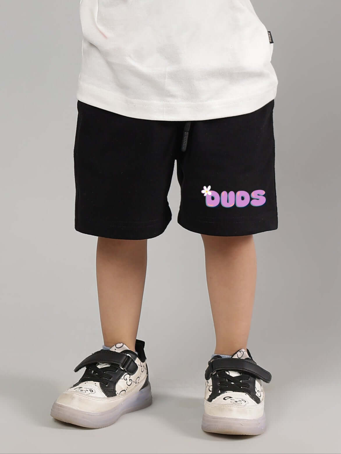 Child wearing black NO POS shorts from DUDS, featuring customizable fit and vibrant logo.