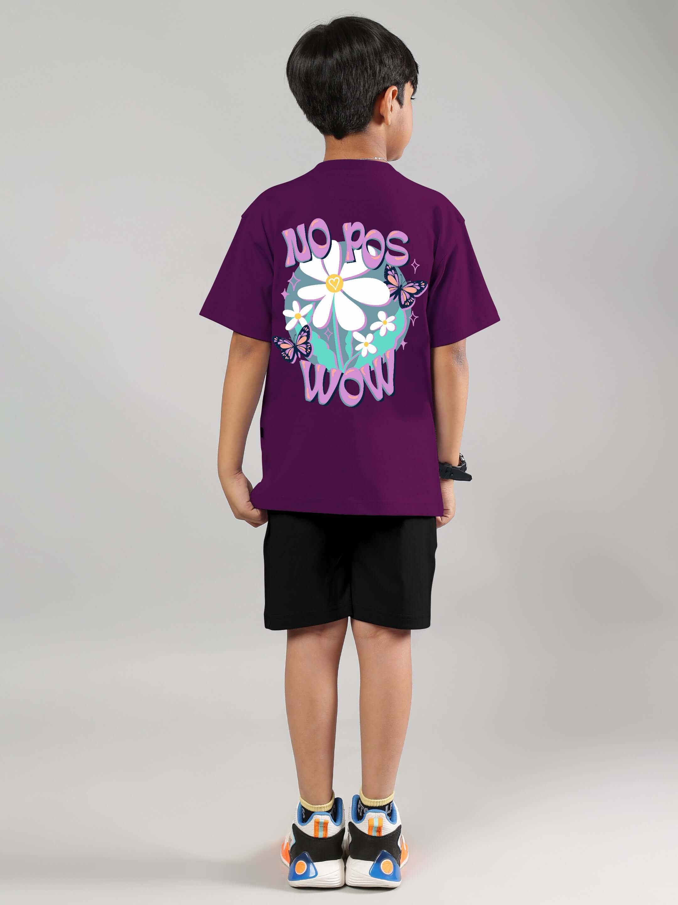 Young child wearing a purple NO POS WOW co-ord set for boys & girls, featuring daisy graphic on the back. Made by DUDS, custom fit available.