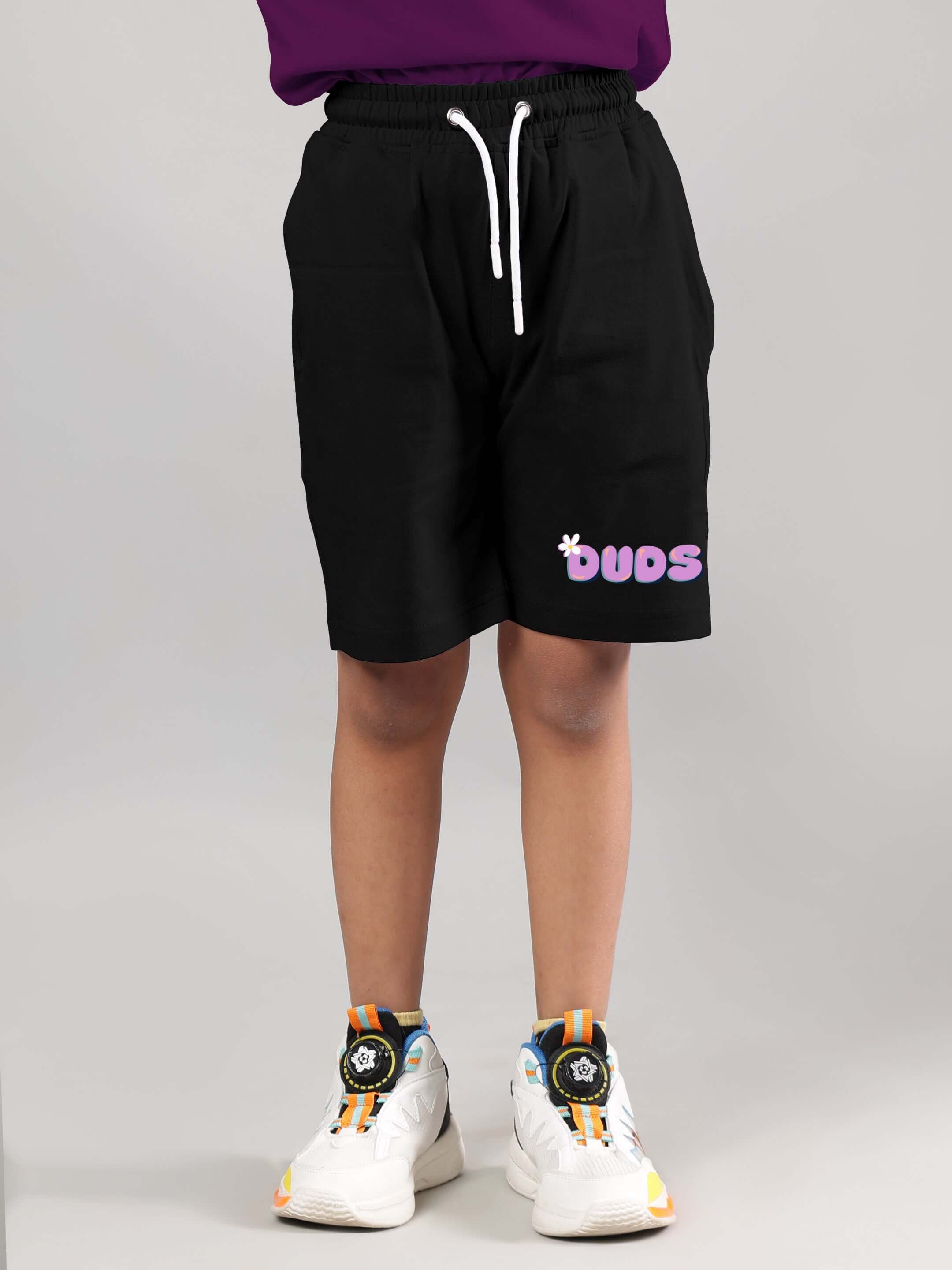 Child wearing NO POS WOW co-ord shorts in black with purple logo from DUDS, customizable fit available, tailored fashion.