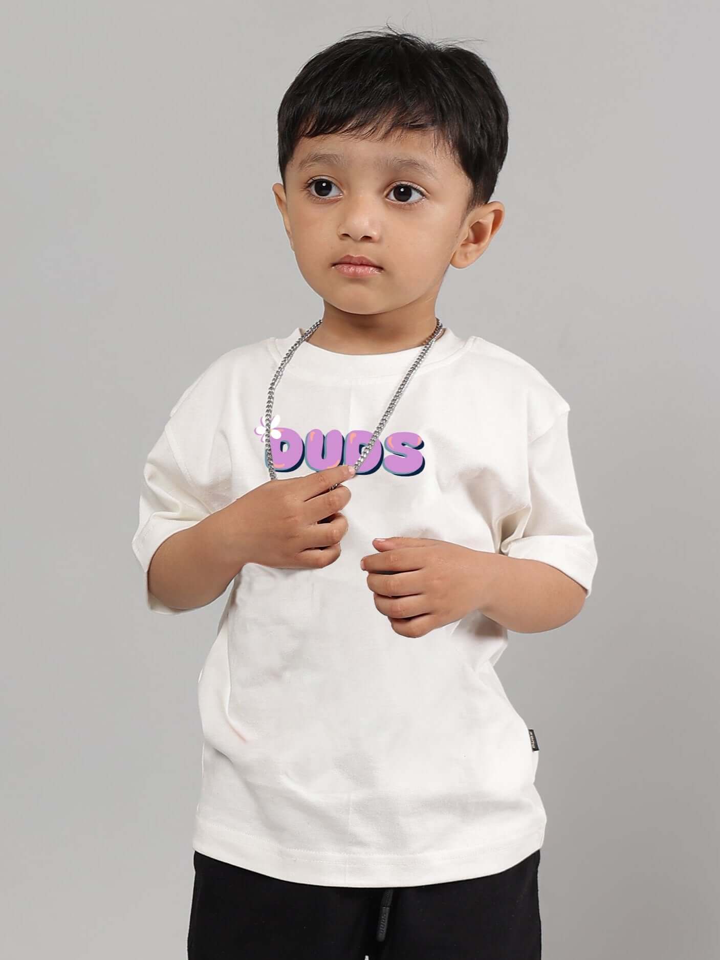 Young child wearing an off-white "NO POS WOW" T-shirt from DUDS, featuring comfortable fit options for boys and girls.