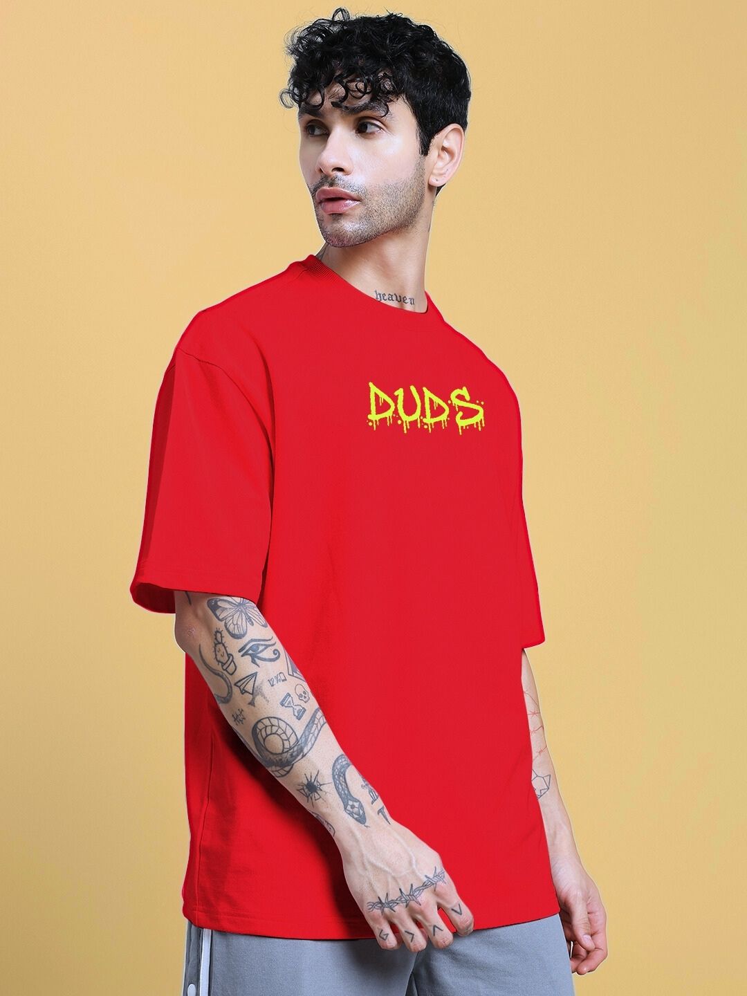 NO WAR OVER-SIZED T-SHIRT IN RED worn by a tattooed male model standing sideways in front of a plain background