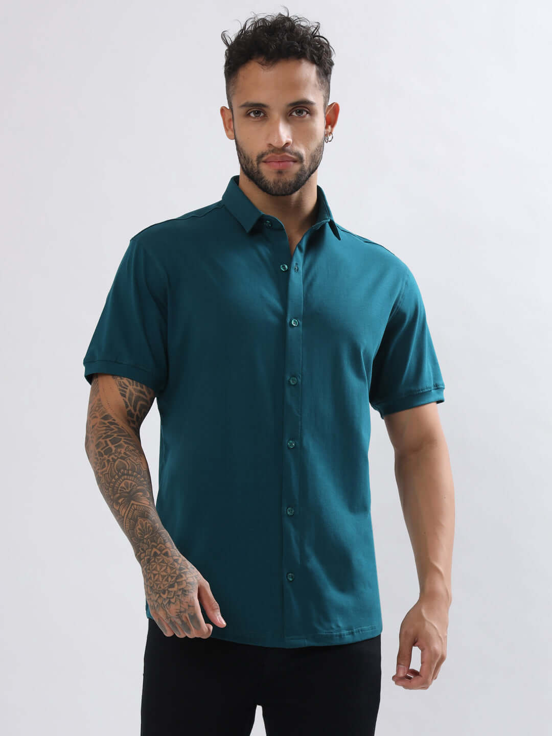 Man wearing a Noir Teal Blue half-sleeve, wrinkle-free shirt, showcasing slim fit and curved hem design. Made of 100% Cotton Lycra.