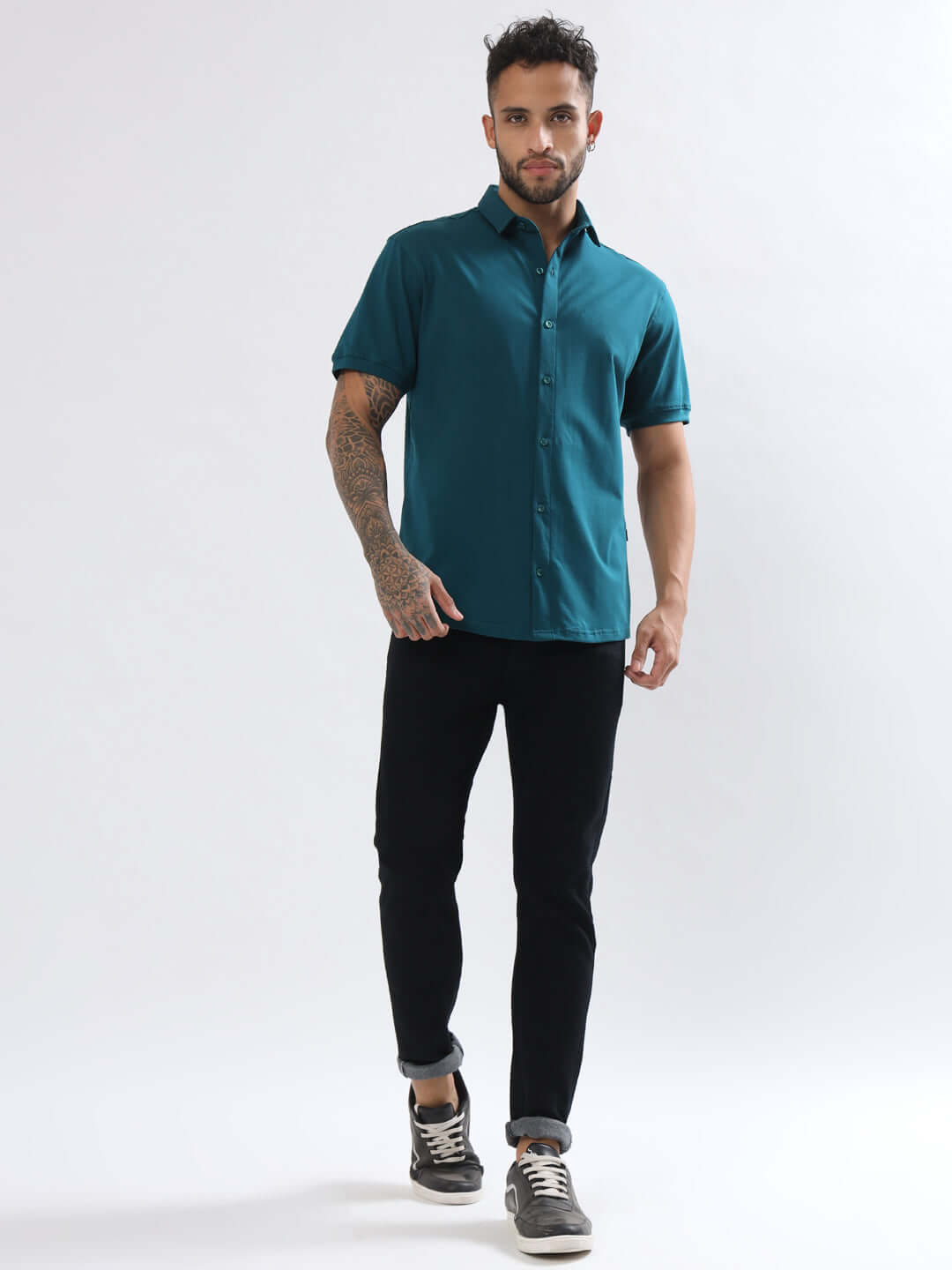 Model wearing a NOIR TEAL BLUE slim fit shirt with 4-way stretch and wrinkle-free fabric, paired with black pants and sneakers.