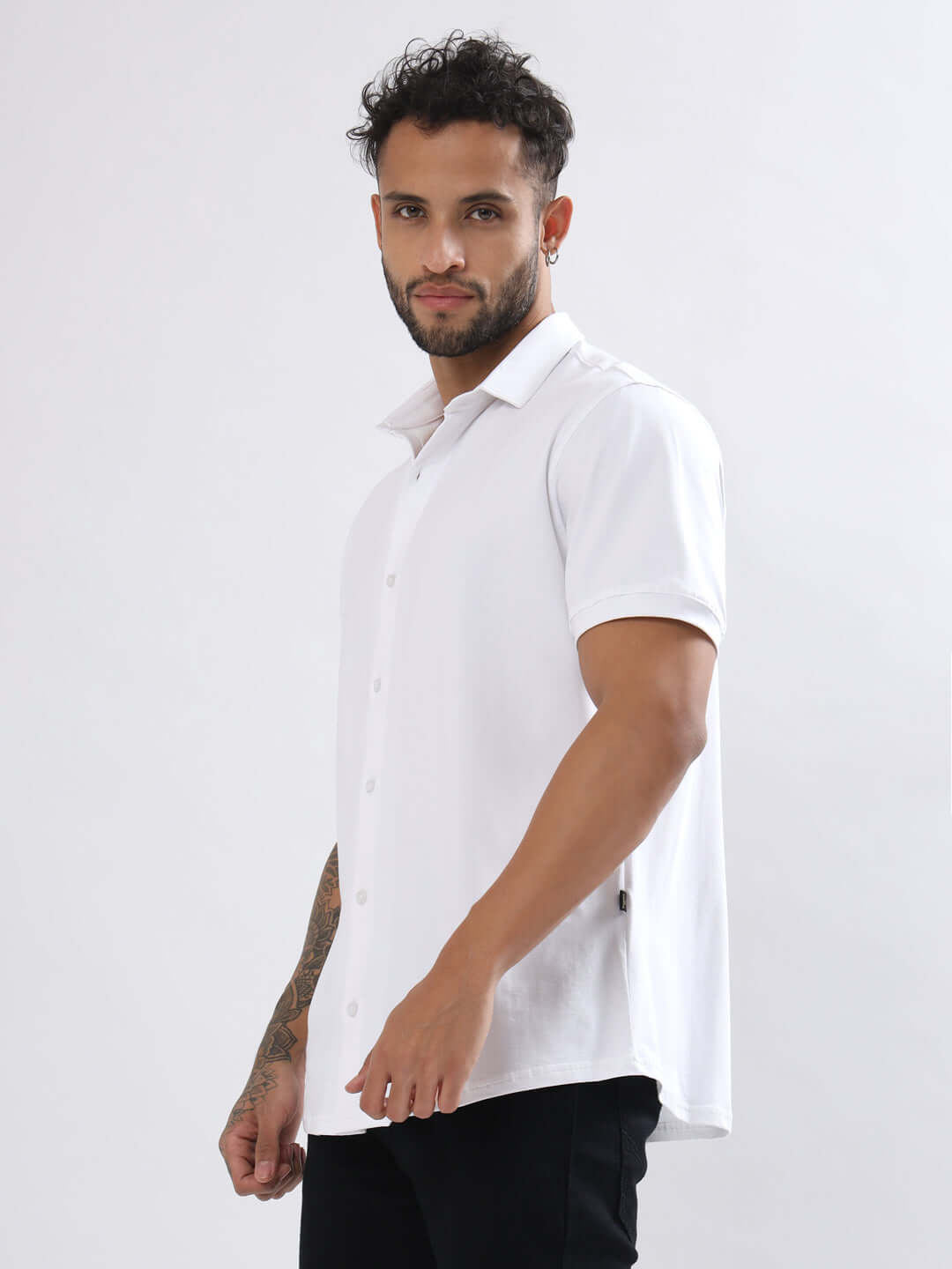 Model wearing NOIR white half-sleeve shirt, slim fit, 4-way stretch, wrinkle-free, made of cotton lycra with a curved hem design.