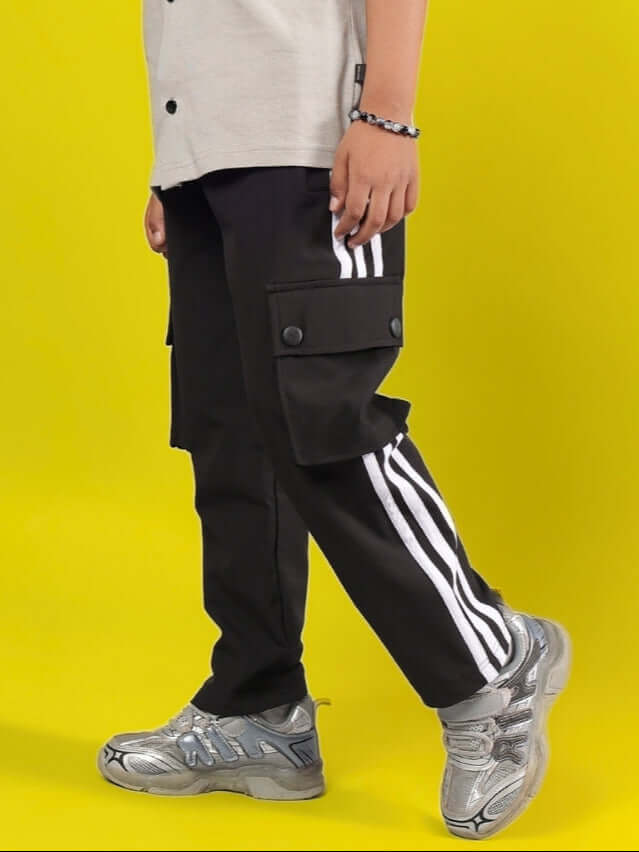 Child wearing NOVA Jogger for Boys & Girls in black with white stripes and pockets against a yellow background.