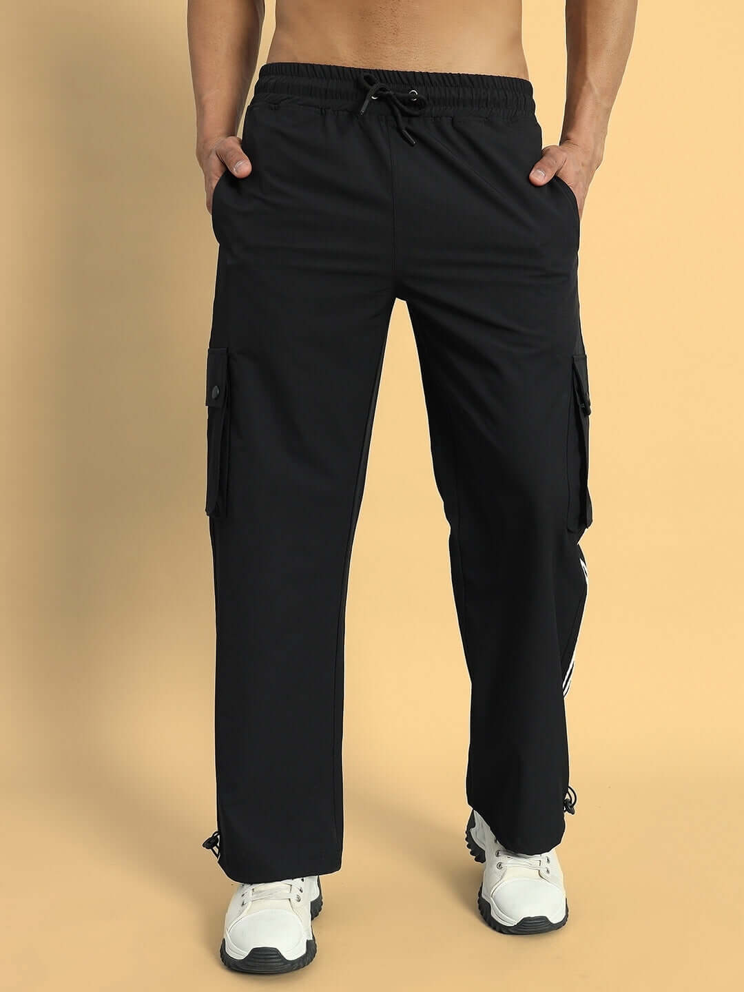 Model wearing Nova Relaxed Fit Cargo Pants in Black with hands in pockets, showcasing customizable fit and stylish design.