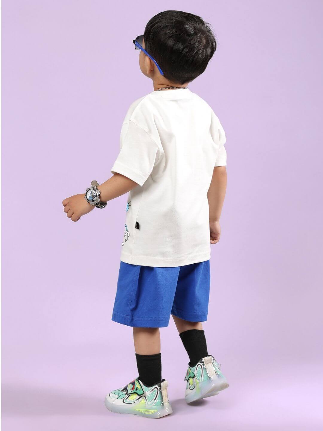 Child wearing OGGY PRINTED CO-ORD SET FOR BOYS AND GIRLS OFF WHITE-BLUE, showcasing back view with stylish accessories.