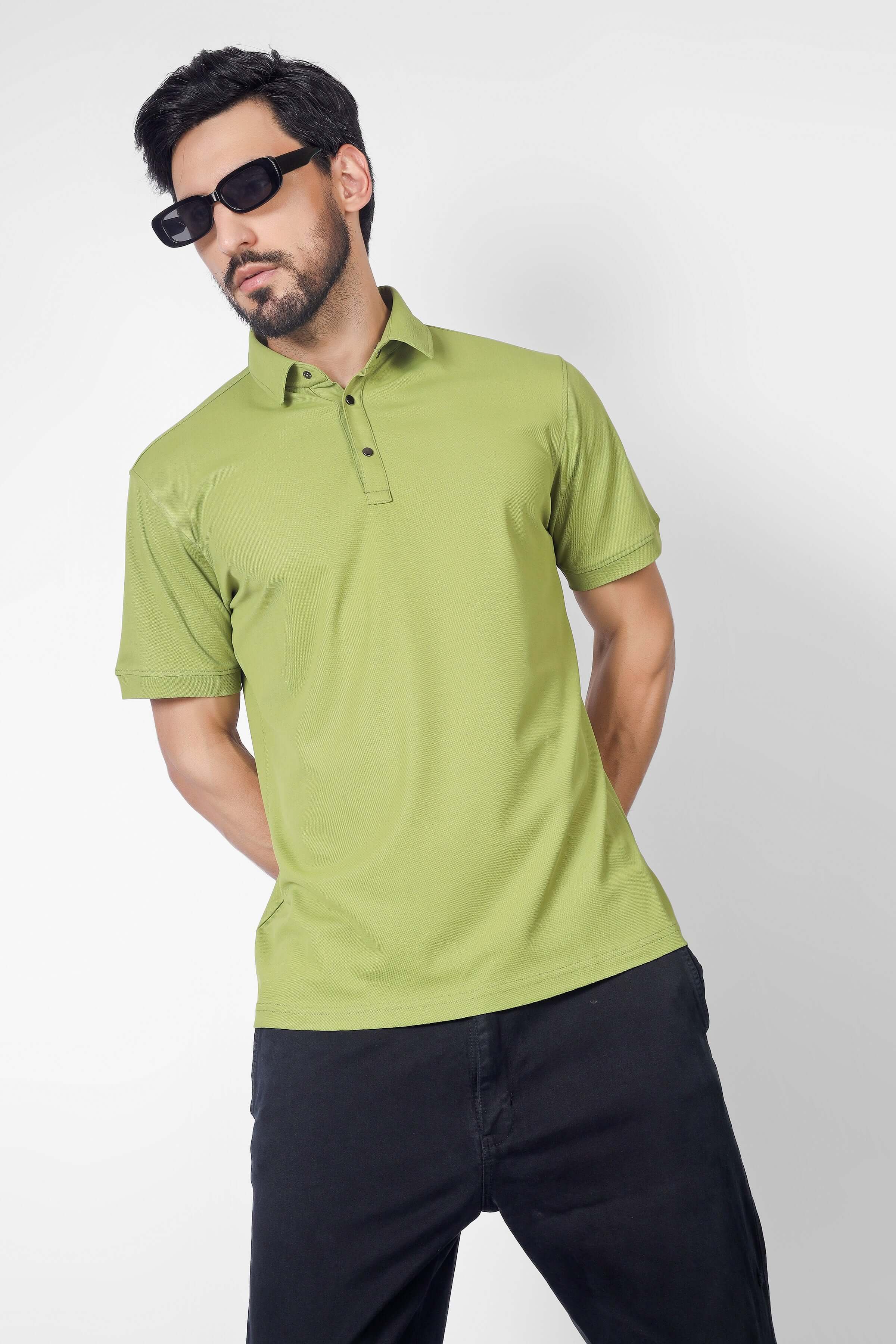 Model wearing an olive green polo neck t-shirt with half sleeves, no fade guarantee, and wrinkle-free fabric, styled with dark pants.