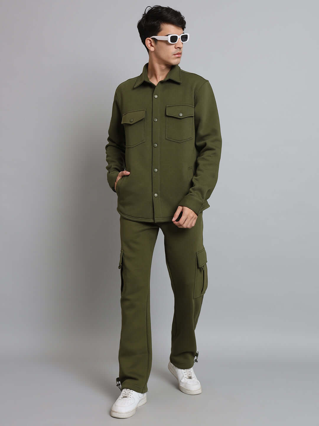 Model wearing olive green relaxed fit fleece cargo pants with matching jacket and white sneakers, casual stylish outfit.