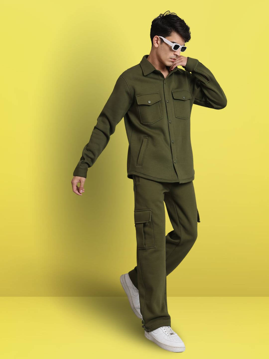 Model wearing OLIVE GREEN RELAXED FIT FULL SLEEVES FLEECE OVERSHIRT with matching pants against a yellow background
