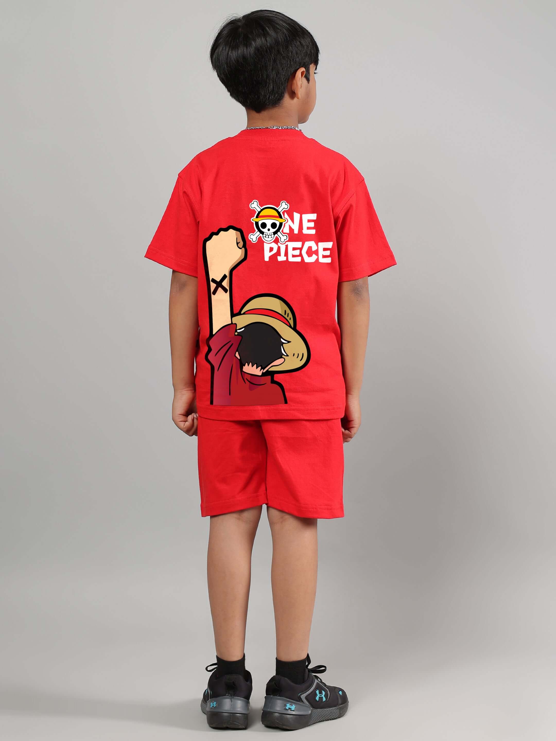 Child wearing a red One Piece summer co-ord set, featuring a graphic of Luffy on the back, tailored by DUDS with customizable sizing.