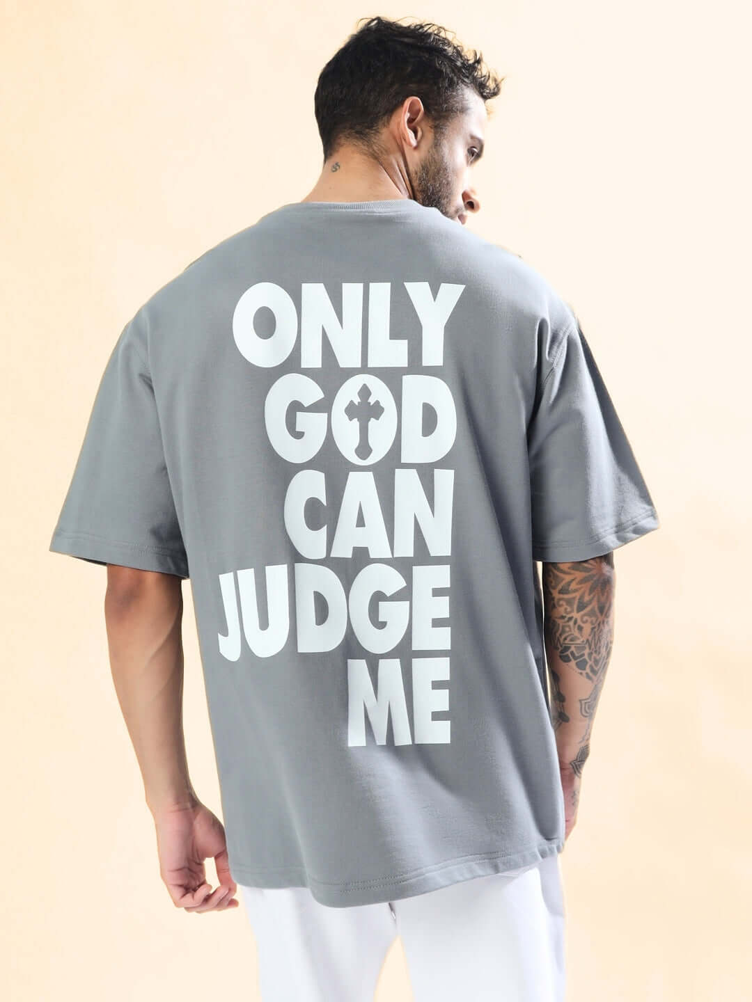 Man wearing grey oversized t-shirt with 'Only God Can Judge Me' text, made of premium cotton fabric; back view for streetwear fashion.