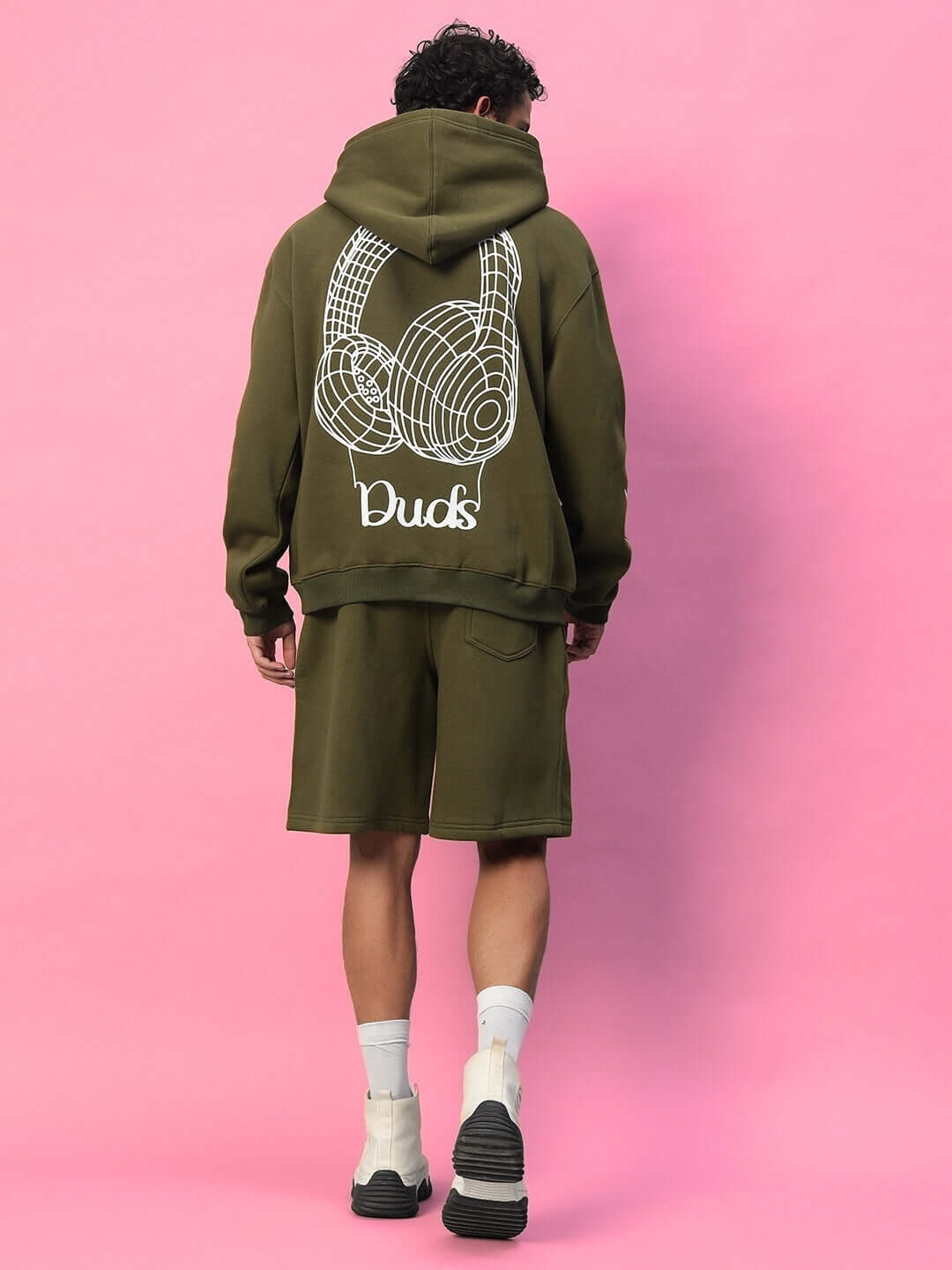 Model wearing OPERA FLEECE CO-ORD OLIVE GREEN with graphic design on back, pink background.