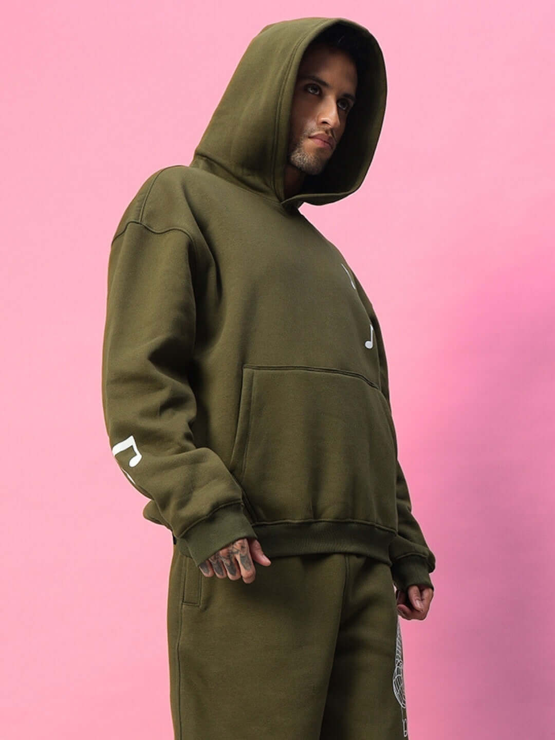 OPERA FLEECE HOODIE OLIVE GREEN on model against pink background.