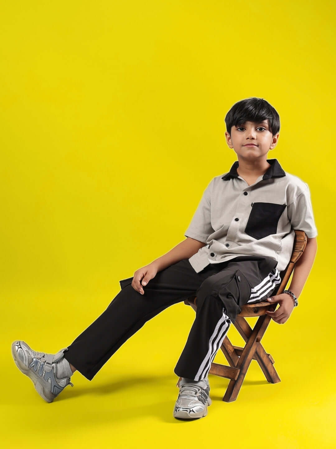 Child wearing ORION CO-ORD FOR BOYS & GIRLS GREY-BLACK sitting on a chair against a yellow background.