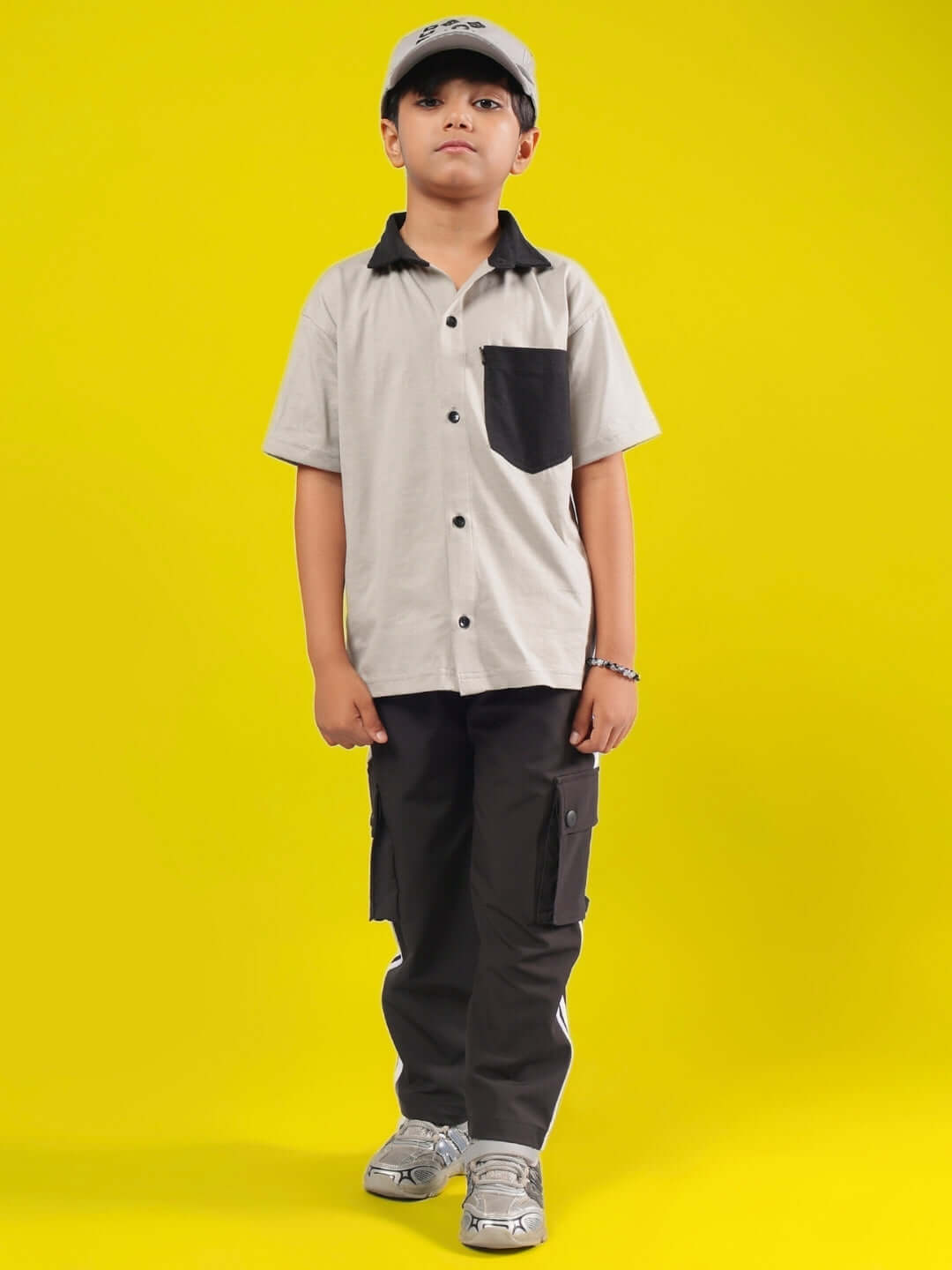 Child wearing ORION CO-ORD FOR BOYS & GIRLS GREY-BLACK outfit, featuring a grey shirt and black pants, standing against a yellow background.