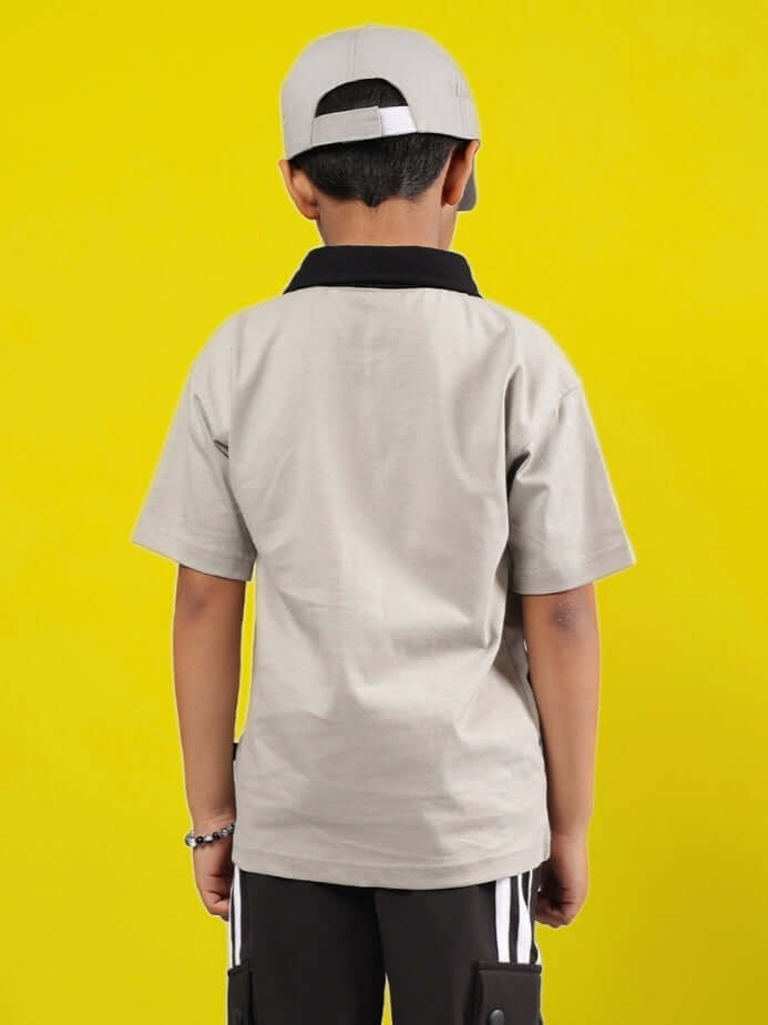 Child wearing grey-black ORION shirt with cap on vibrant yellow background, showcasing back design and comfortable fit.
