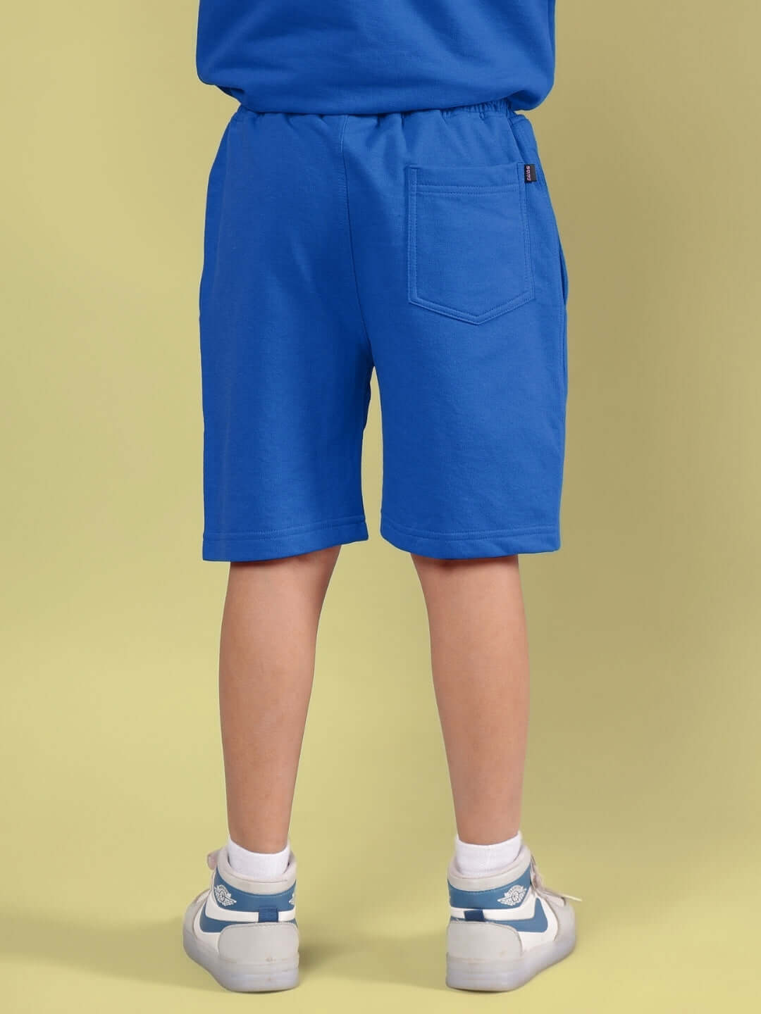 Child wearing a blue OUTLOOK HALF CO-ORD FOR BOYS GIRLS BLUE, showing back view of shorts in vibrant color on neutral background.