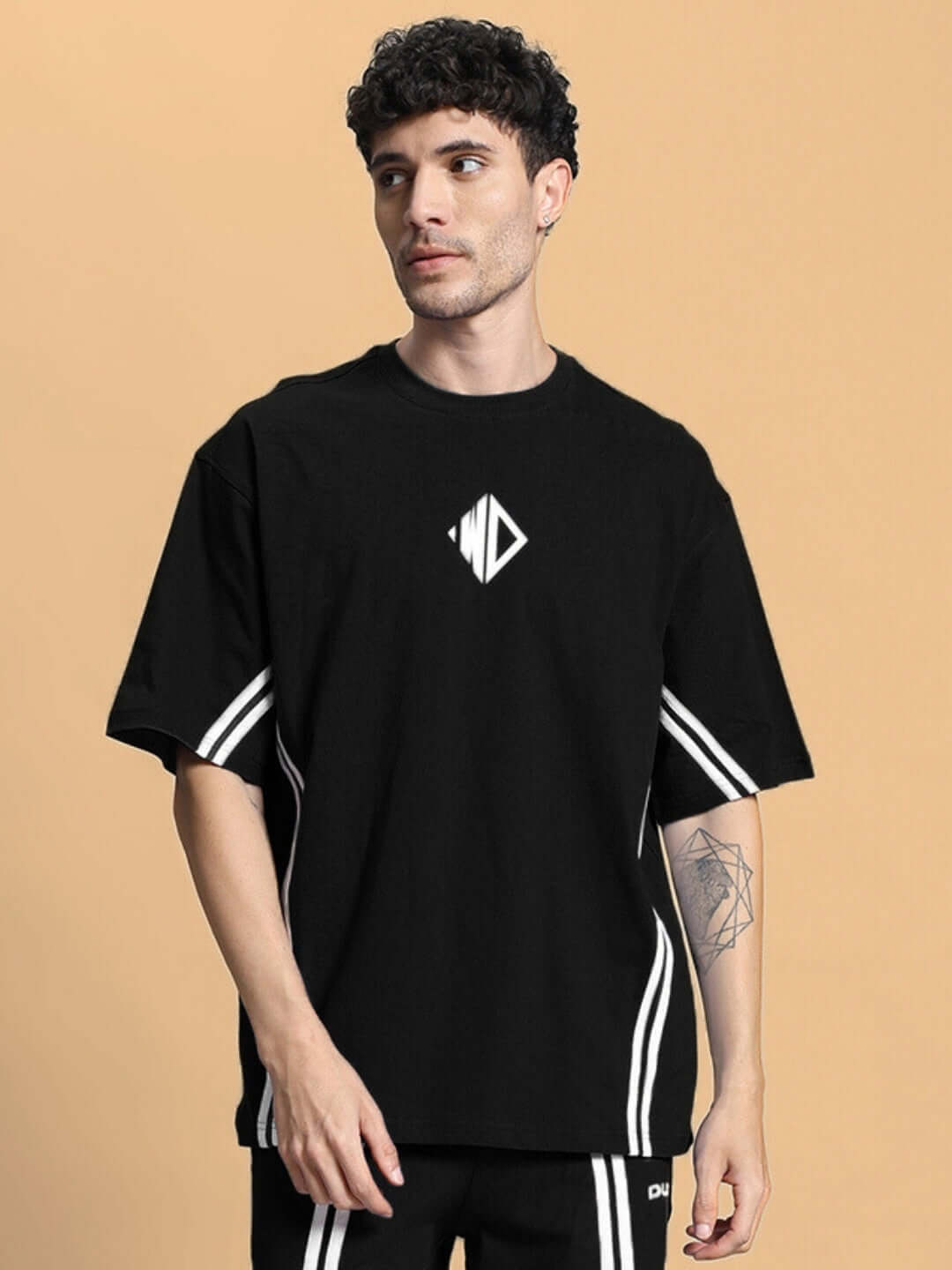 Model wearing black oversized T-shirt made from premium cotton French terry fabric, featuring geometric logo and sporty design.
