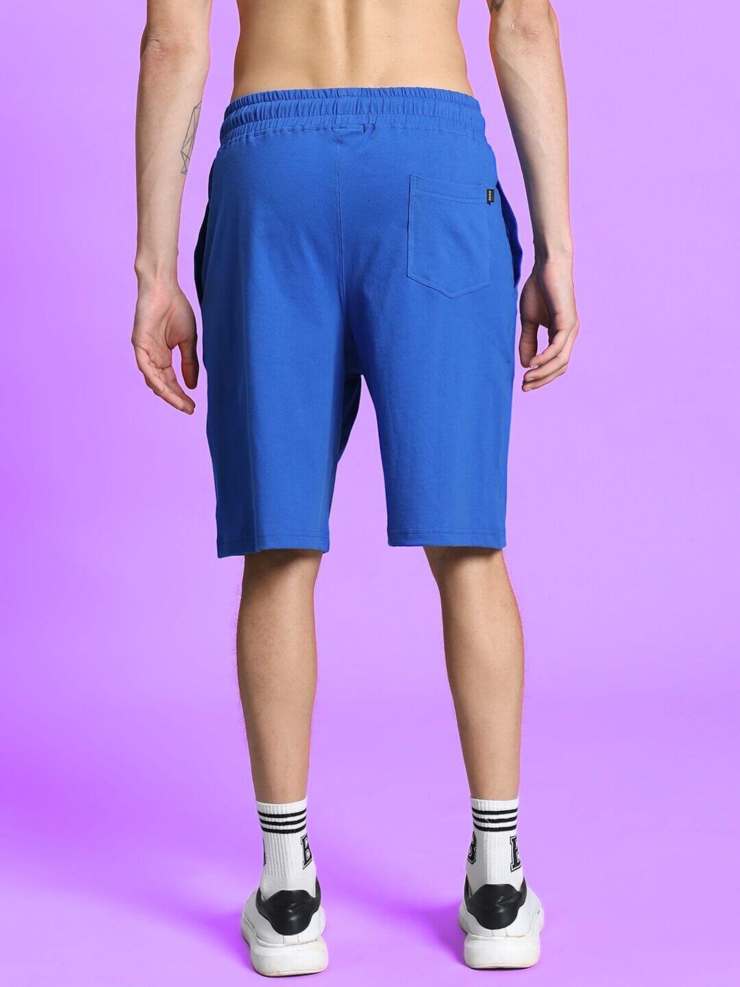 OUTLOOK REGULAR FIT SHORTS ROYAL BLUE shown from the back on a model against a purple background, highlighting comfort and vibrant color.