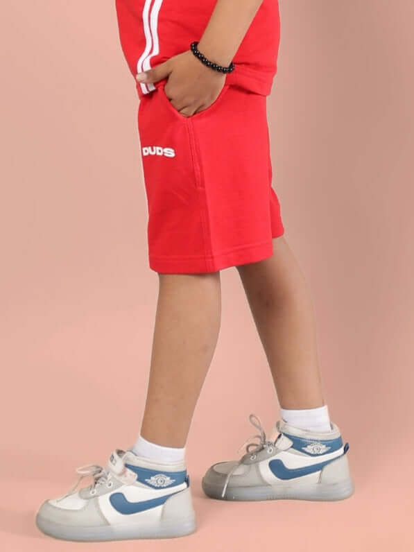 Child wearing OUTLOOK SHORTS FOR BOYS GIRLS RED with sneakers