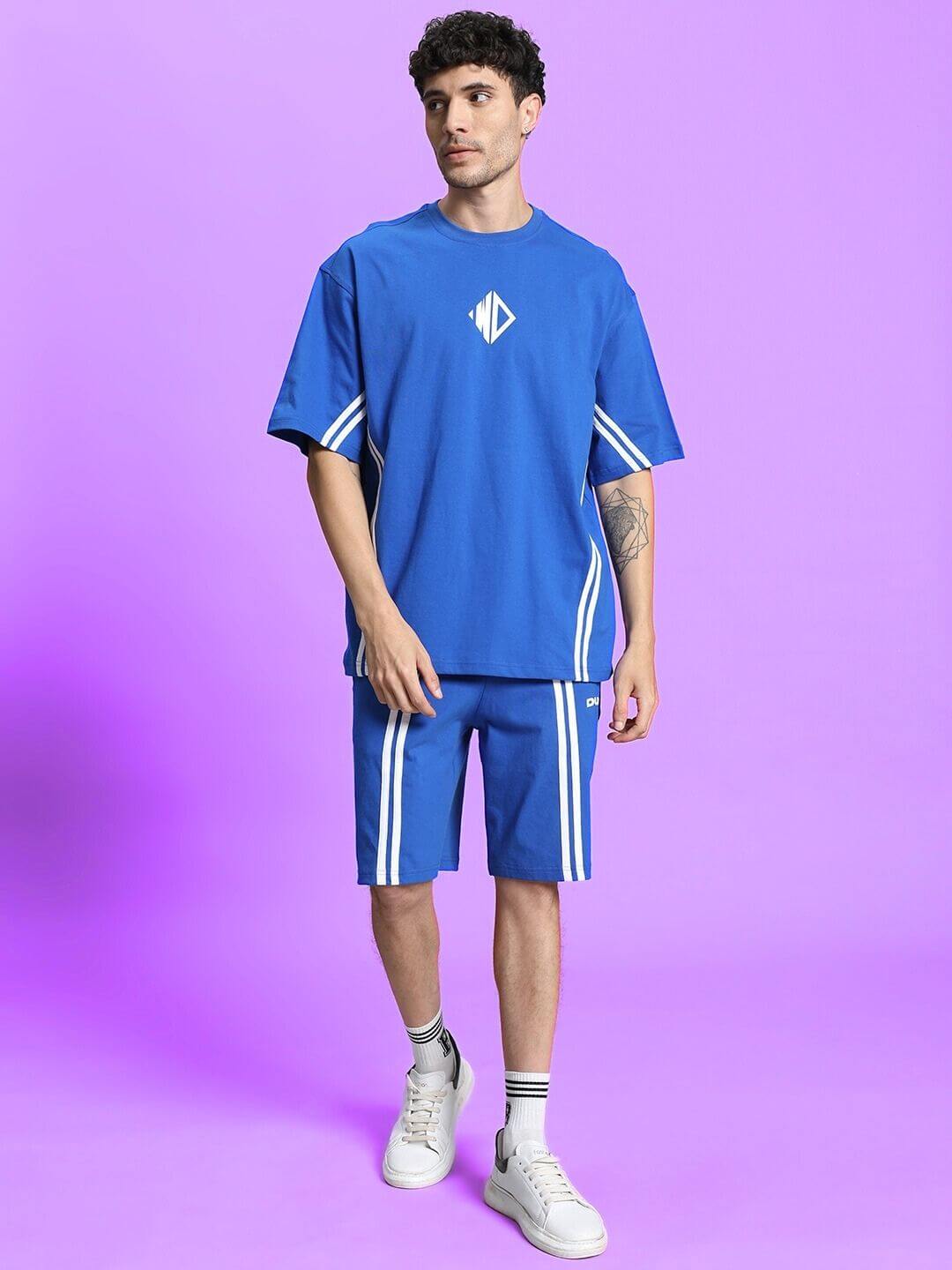Model wearing OUTLOOK SUMMER CO-ORD SHORTS SET in royal blue, made of cotton French terry lycra, on a purple background.