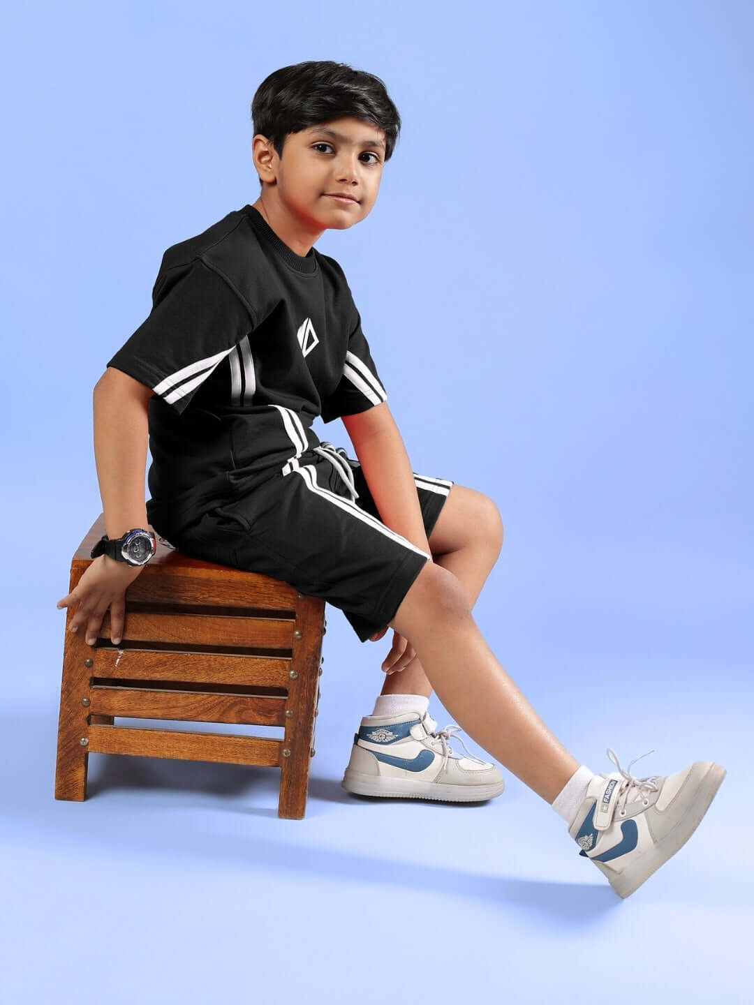 OUTLOOK T-SHIRT FOR BOYS GIRLS BLACK worn by child sitting on a wooden stool, showcasing stylish and comfortable kids' fashion.