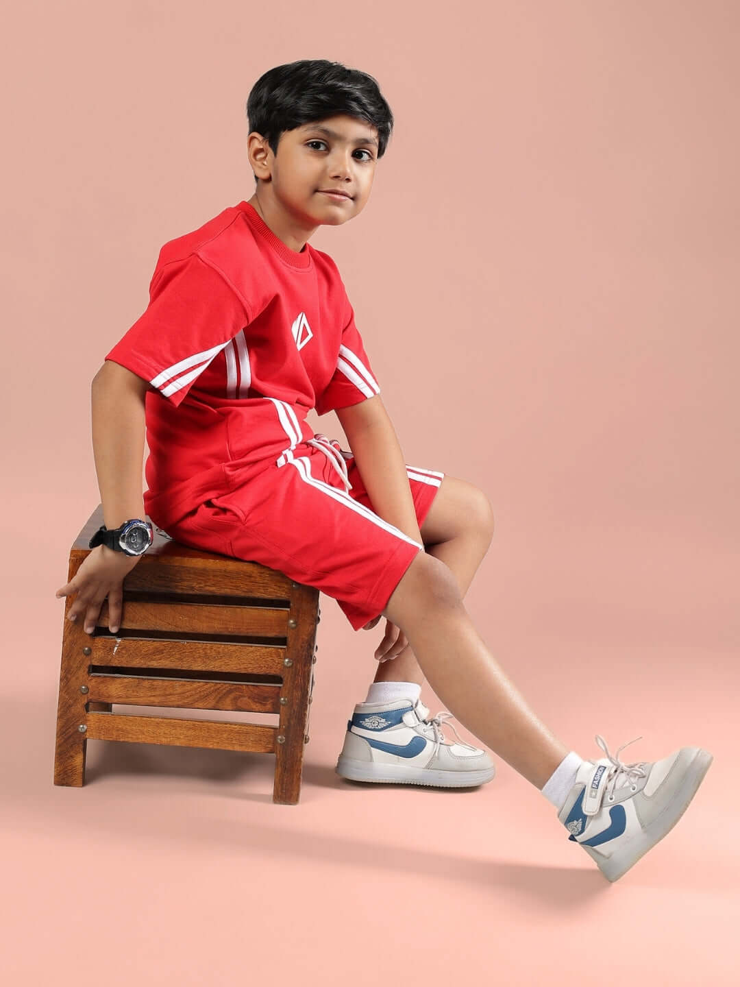 Boy wearing red Outlook Half Co-Ord set sitting on a wooden stool, showcasing casual style for kids.