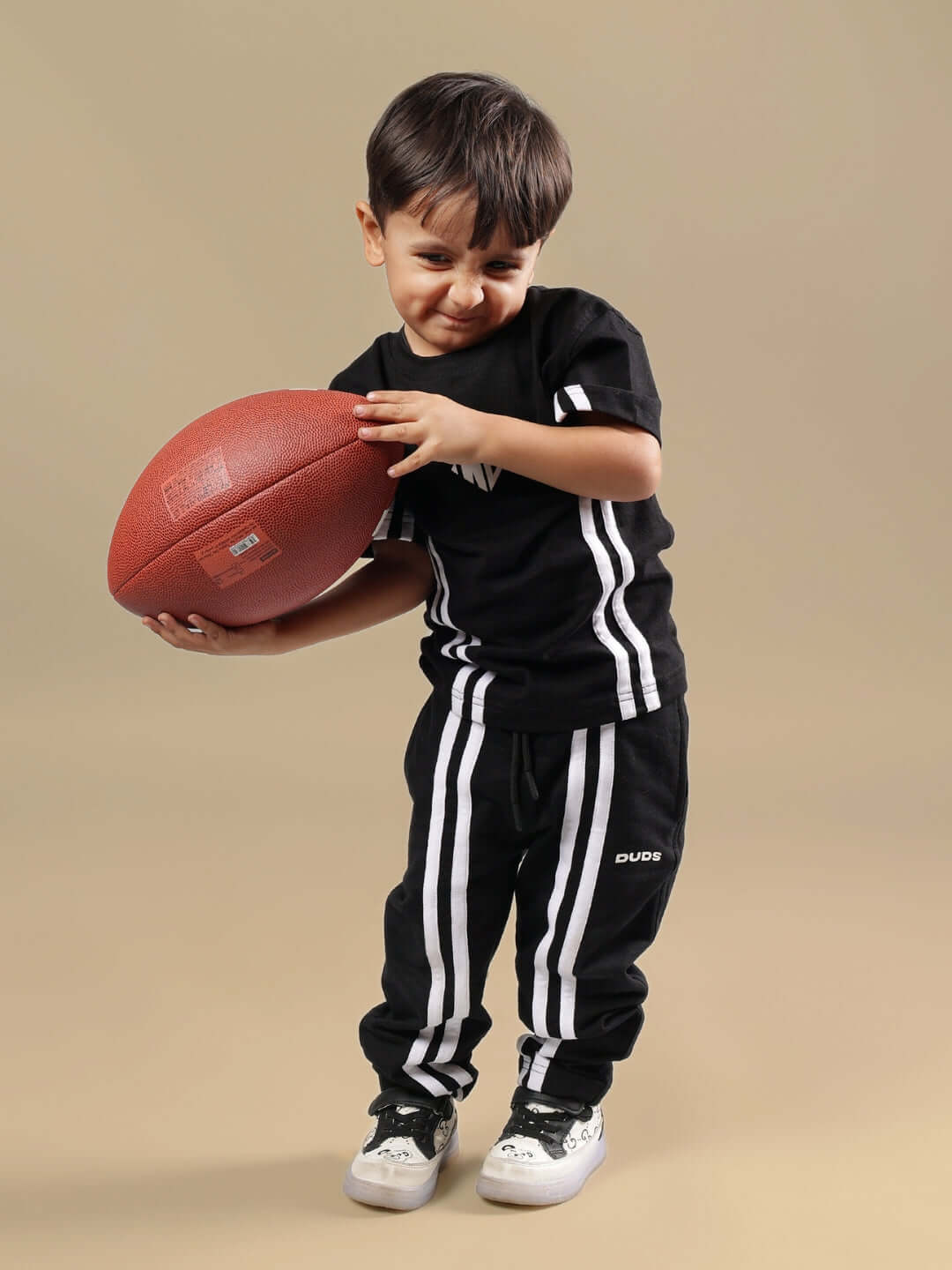 Young boy wearing black summer co-ord set by DUDS holding a football, showcasing comfortable sporty kids' apparel.