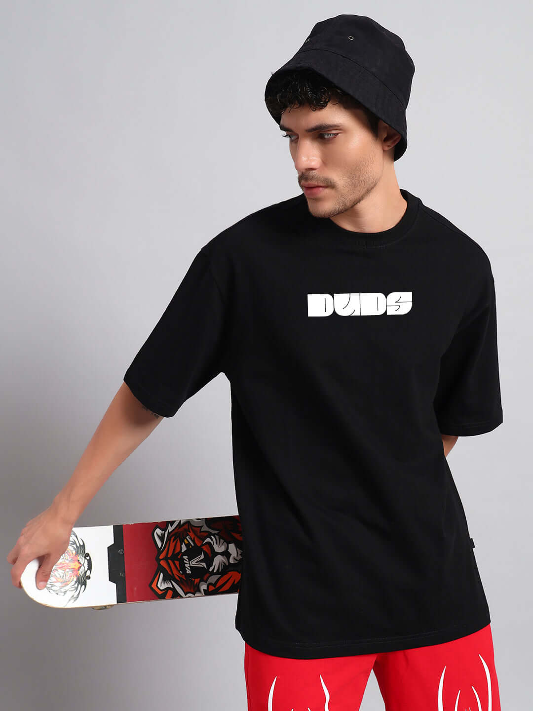 Man wearing a black oversized t-shirt with skate graphics, similar to Guns and Roses style.