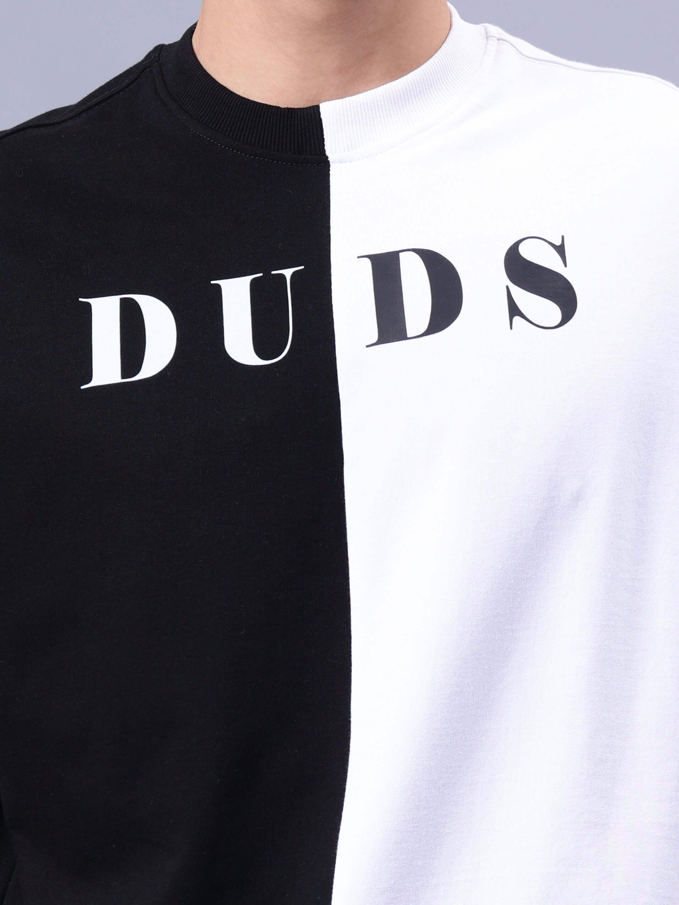 Black and white oversized T-shirt with 'DUDS' text, made from premium cotton blend fabric, showcasing its stylish half-tone design.