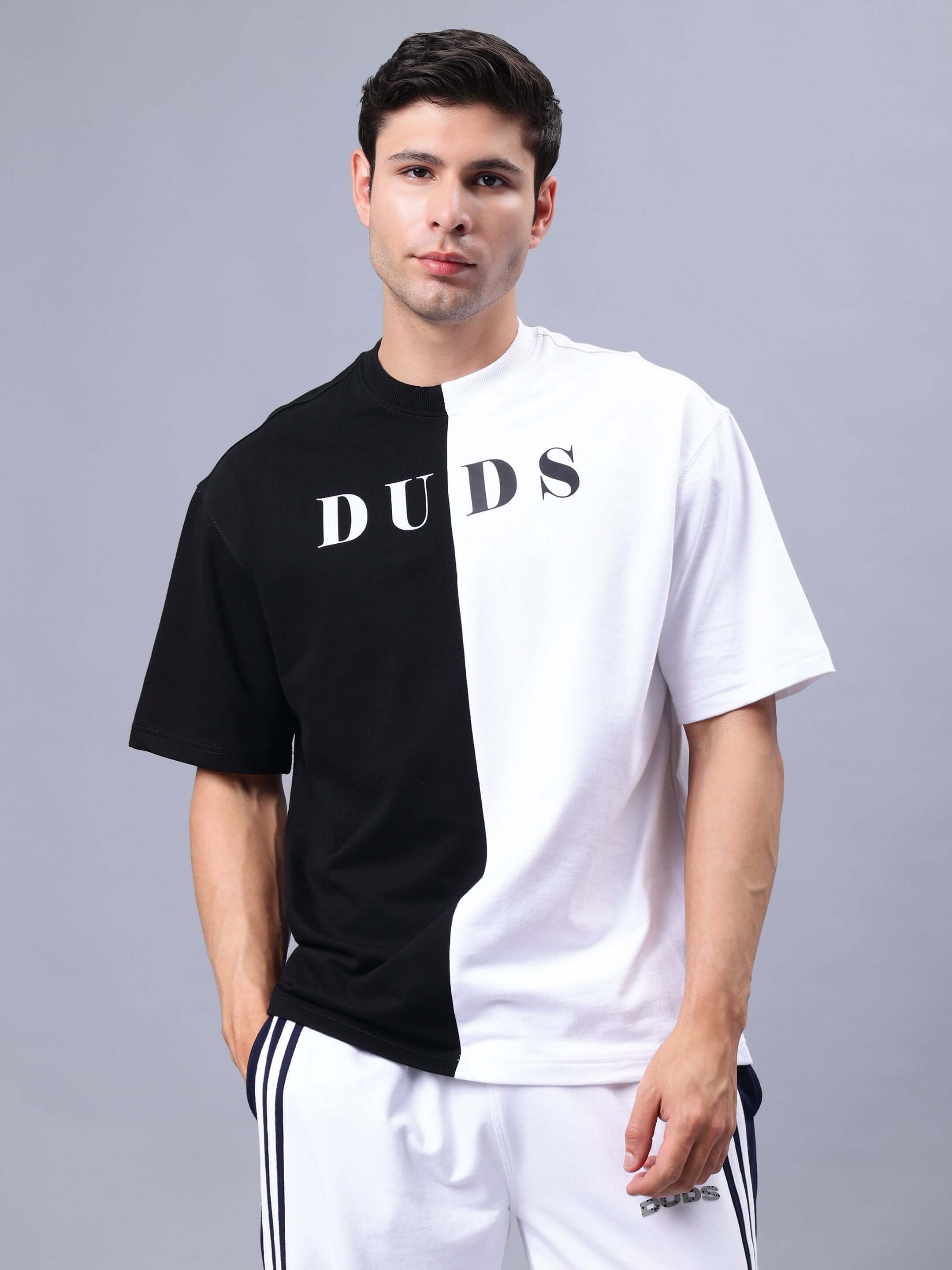 Man wearing G.O.A.T oversized black and white t-shirt made from premium cotton blend, standing against a neutral background.