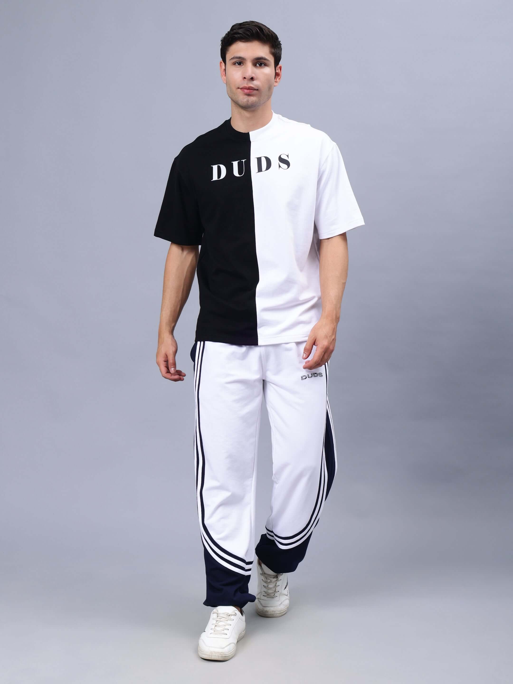 Man wearing G.O.A.T oversized black-white t-shirt made of heavy gauge fabric, showcasing stylish casual wear in a studio setting.