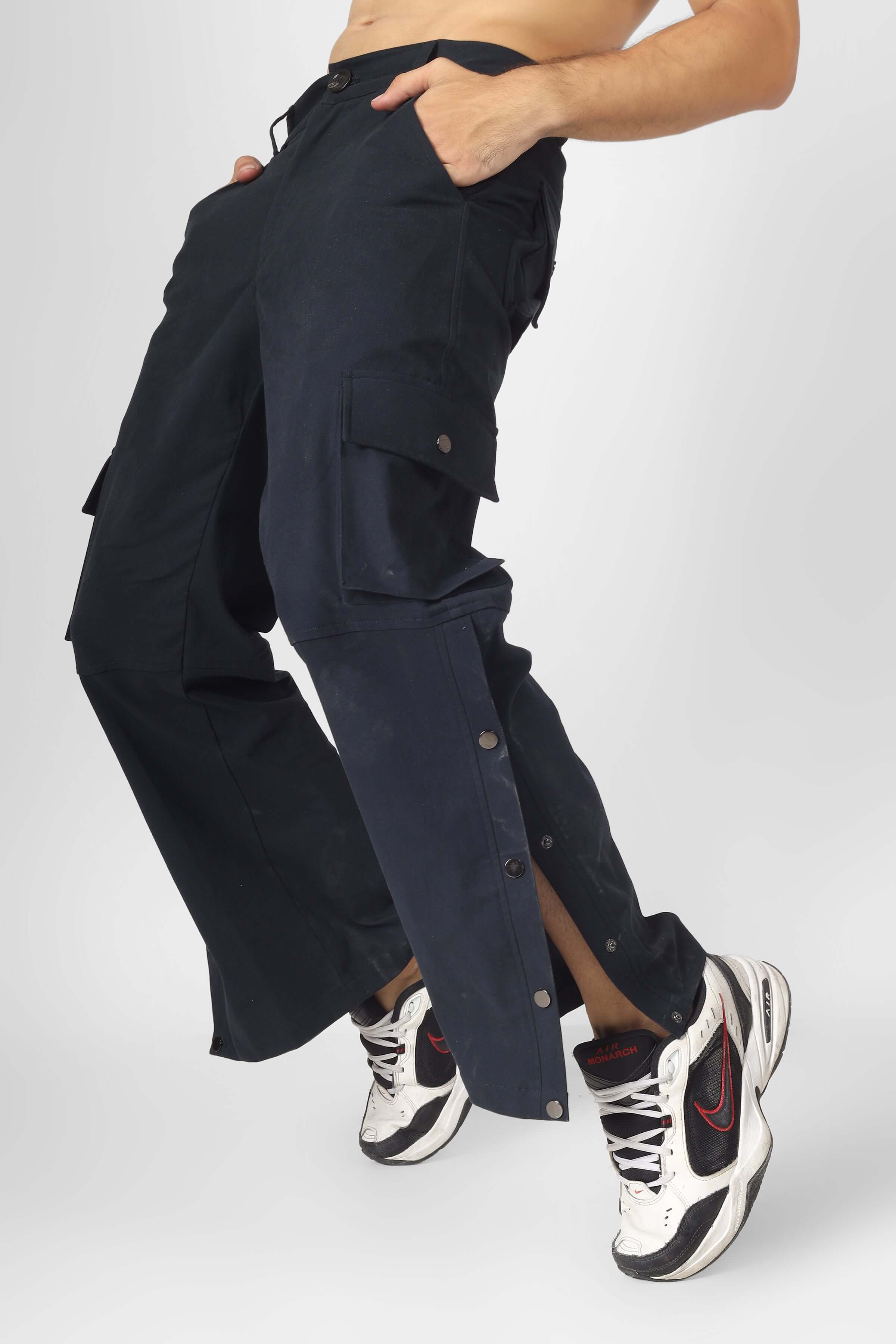 Oxford blue cargo pants with six pockets, worn by a model, showcasing button details and sporty sneakers.